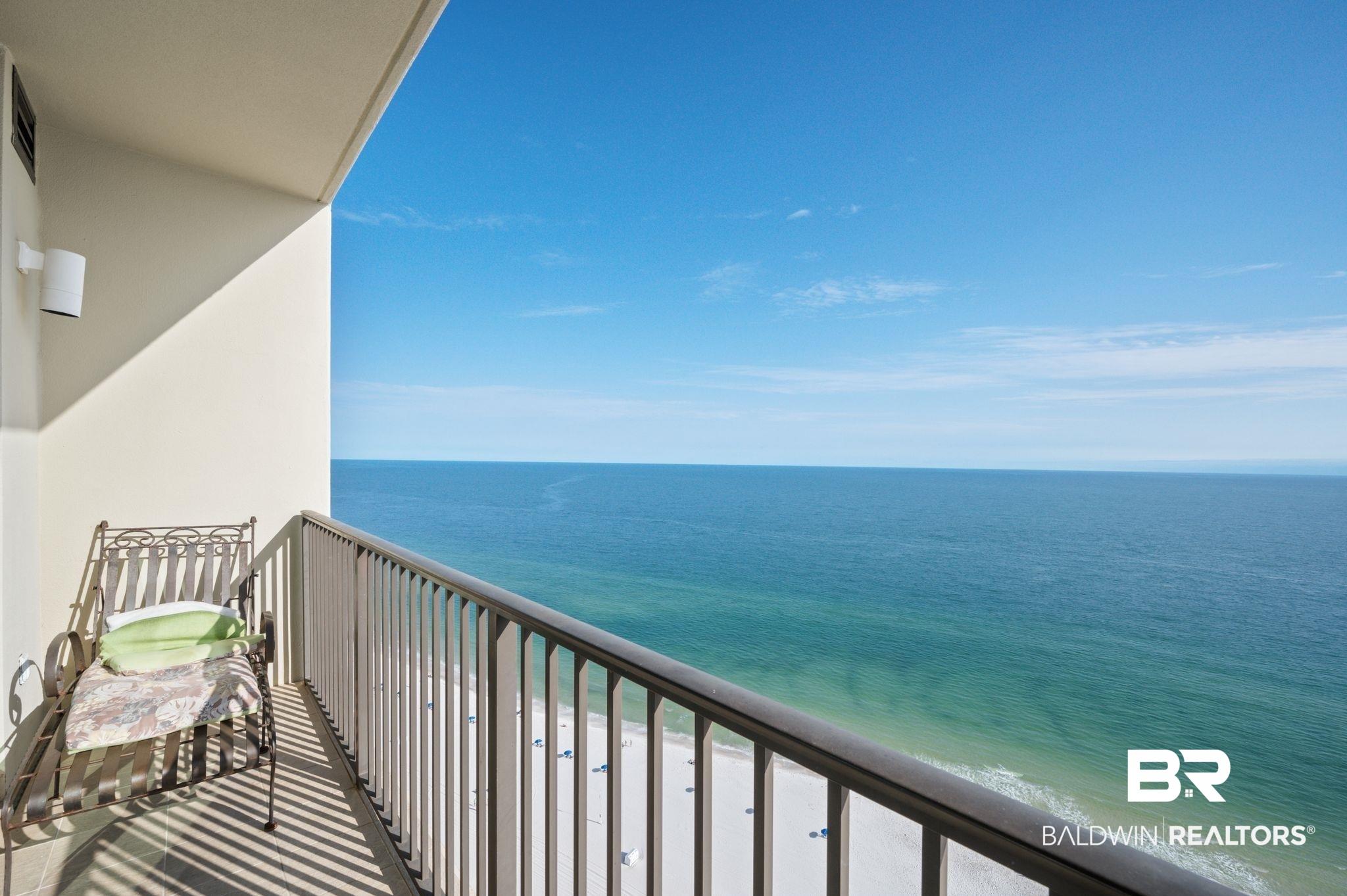 Image 2: Balcony featuring a metal railing, direct ocean frontage, white sand beach, and expansive water scenery