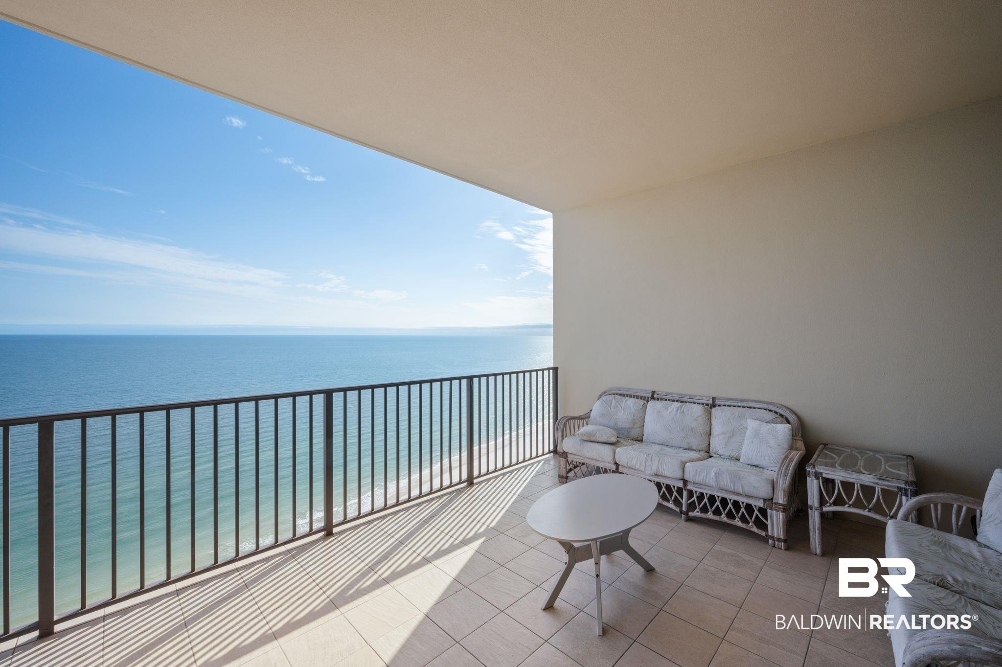 Image 3: Spacious outdoor balcony featuring tile flooring and a black metal railing overlooking the expansive ocean
