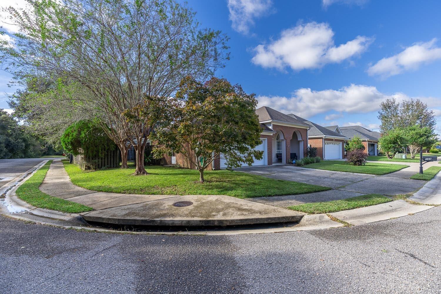 Image 2: View of front of home featuring a front lawn, driveway, brick siding, and an attached garage