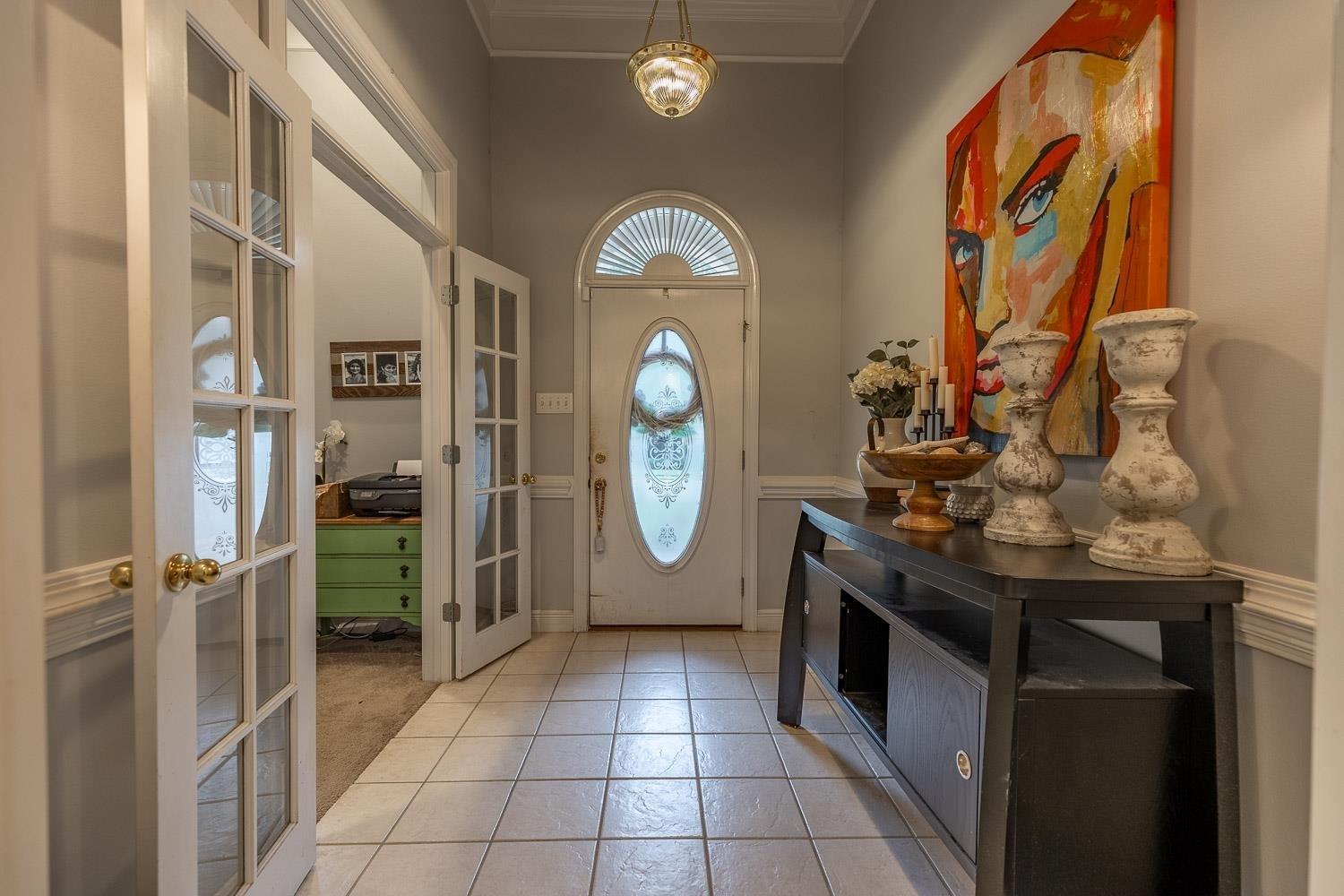 Image 4: Entryway featuring french doors, a towering ceiling, light tile patterned floors, and crown molding