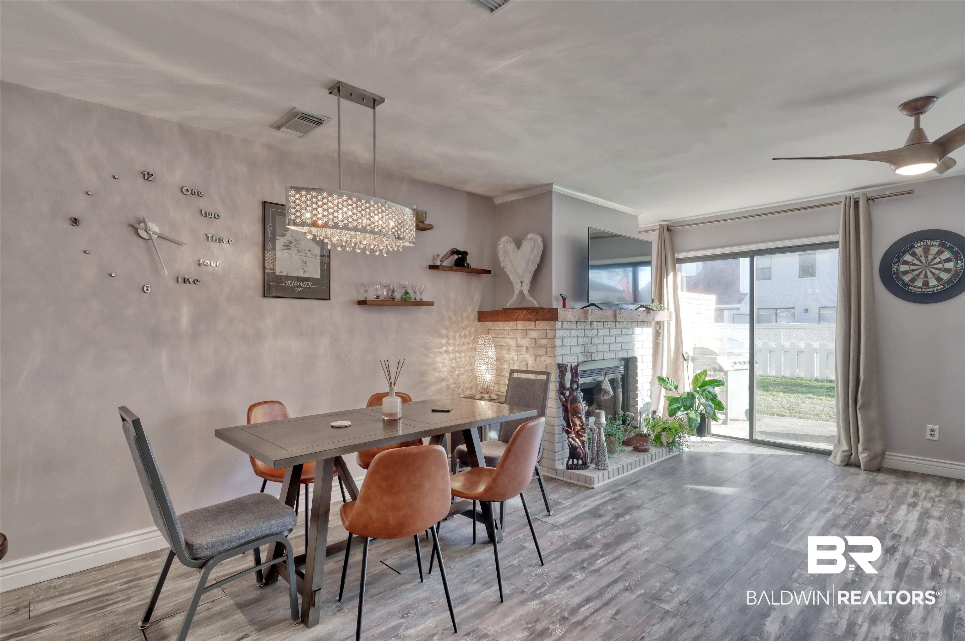 Image 4: Dining space with a fireplace, wood finished floors, ceiling fan, and a chandelier