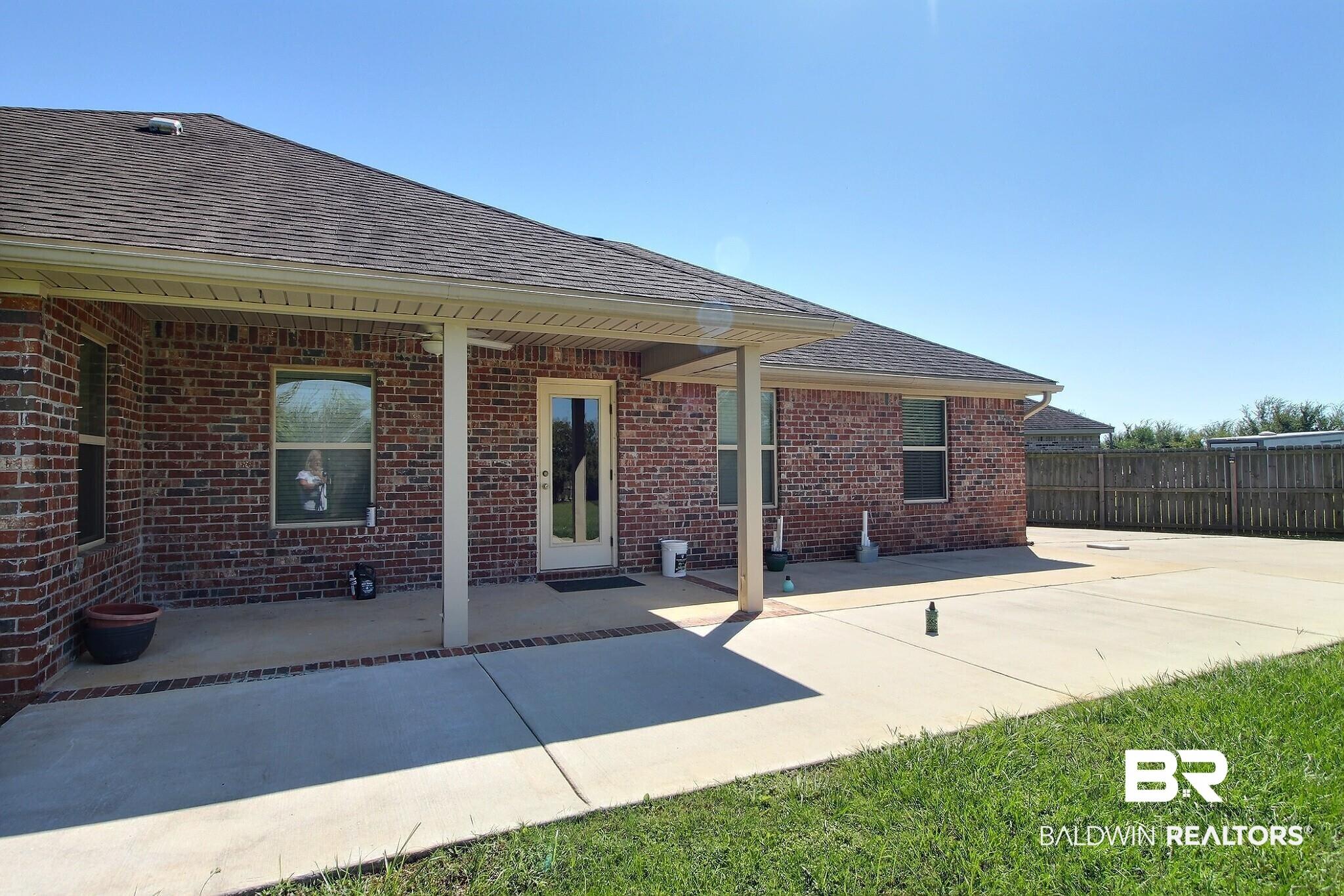 Image 2: Back of house featuring brick siding, a patio area, and roof with shingles