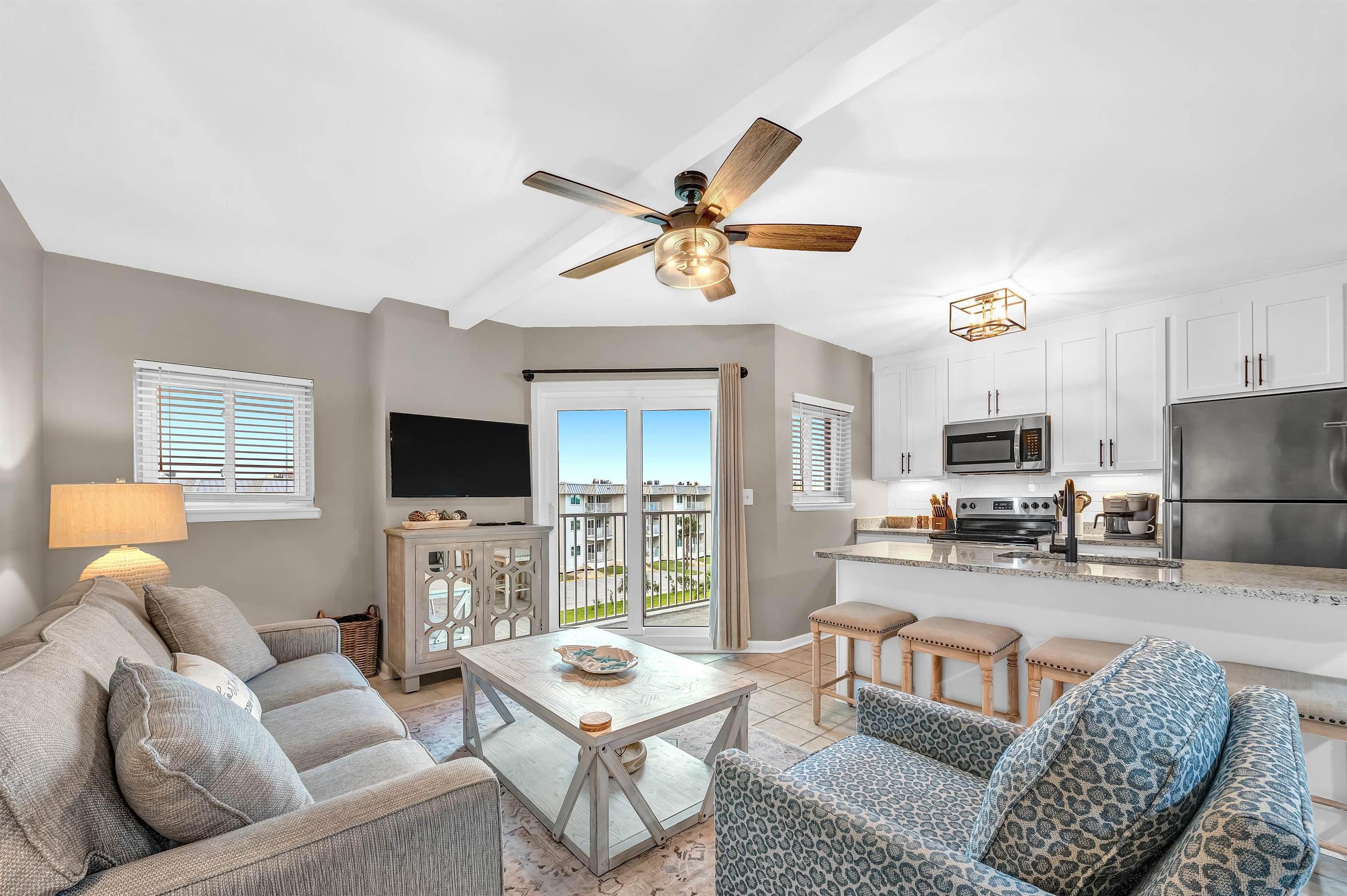 Image 3: Living room with a ceiling fan, beam ceiling, and light tile patterned floors