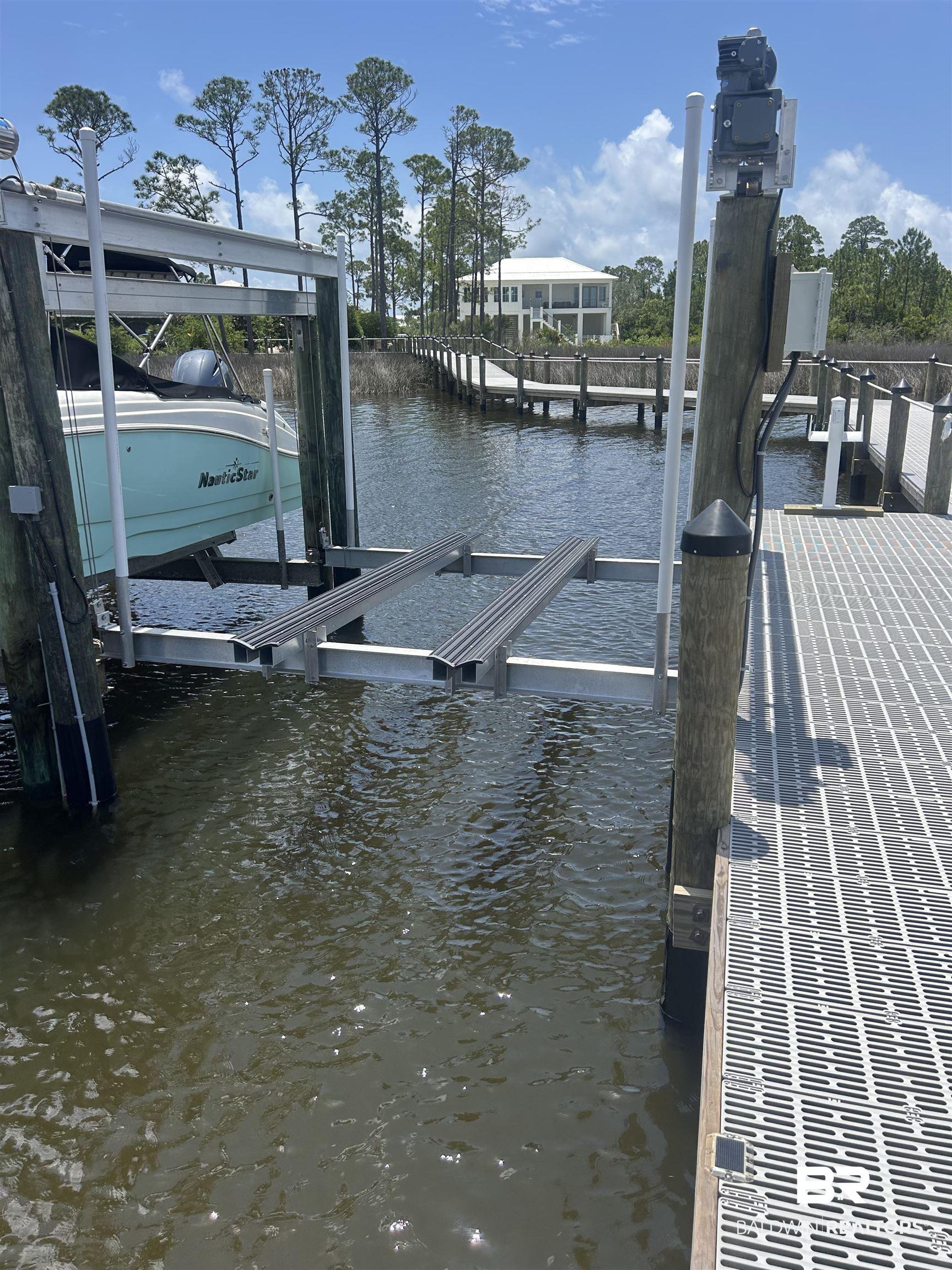 Image 2: Dock featuring boat lift and a water view