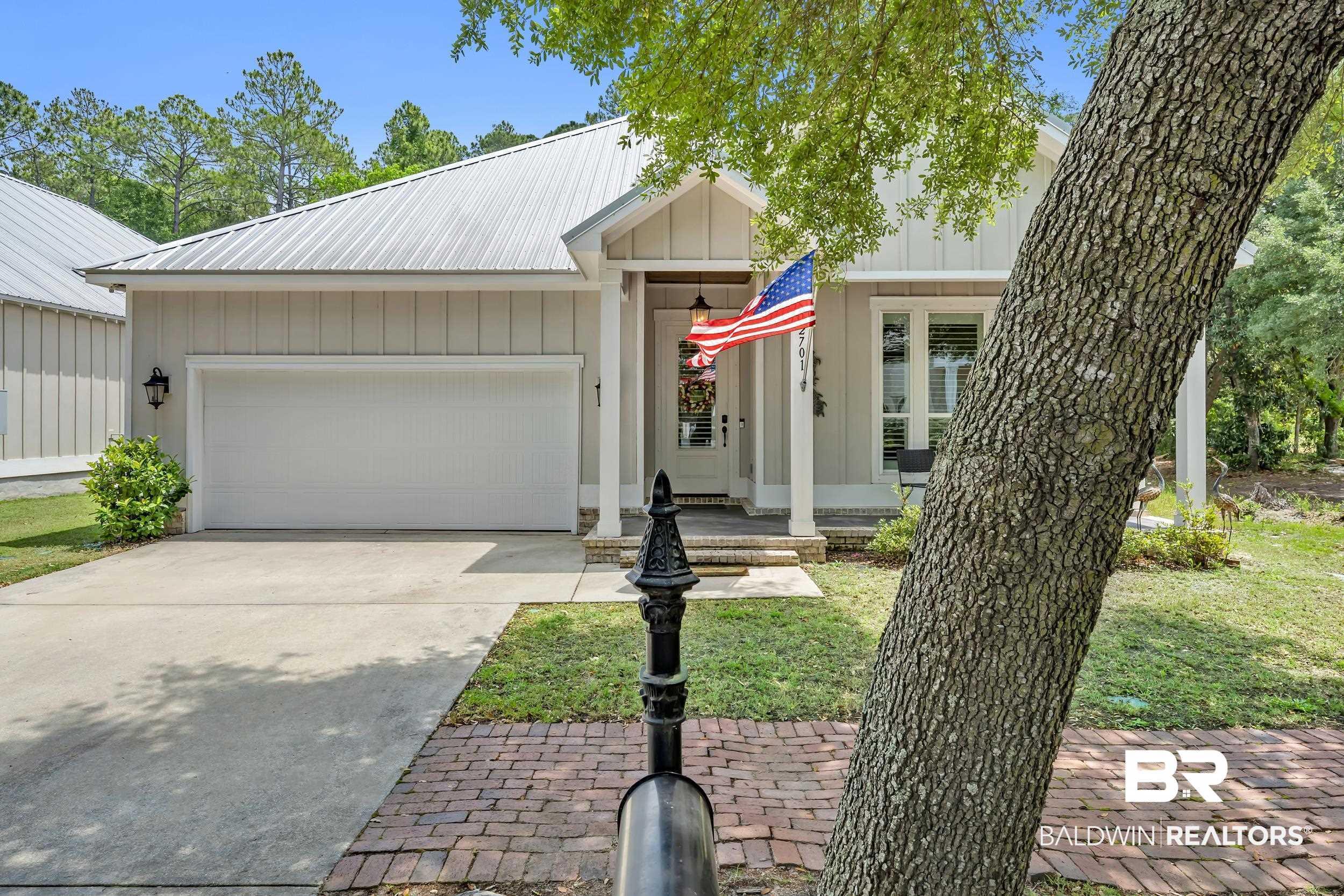Image 2: Exterior featuring a metal roof, board and batten siding, a single-car garage, covered entry porch, and a brick paver walkway
