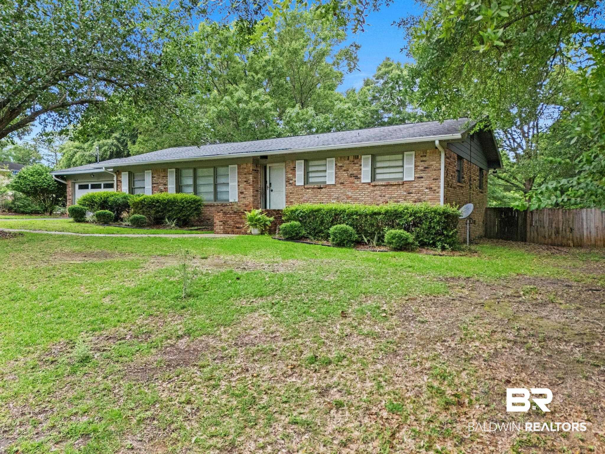 Image 2: Brick exterior residence with a single-car garage, white shutter accents, and established front landscaping