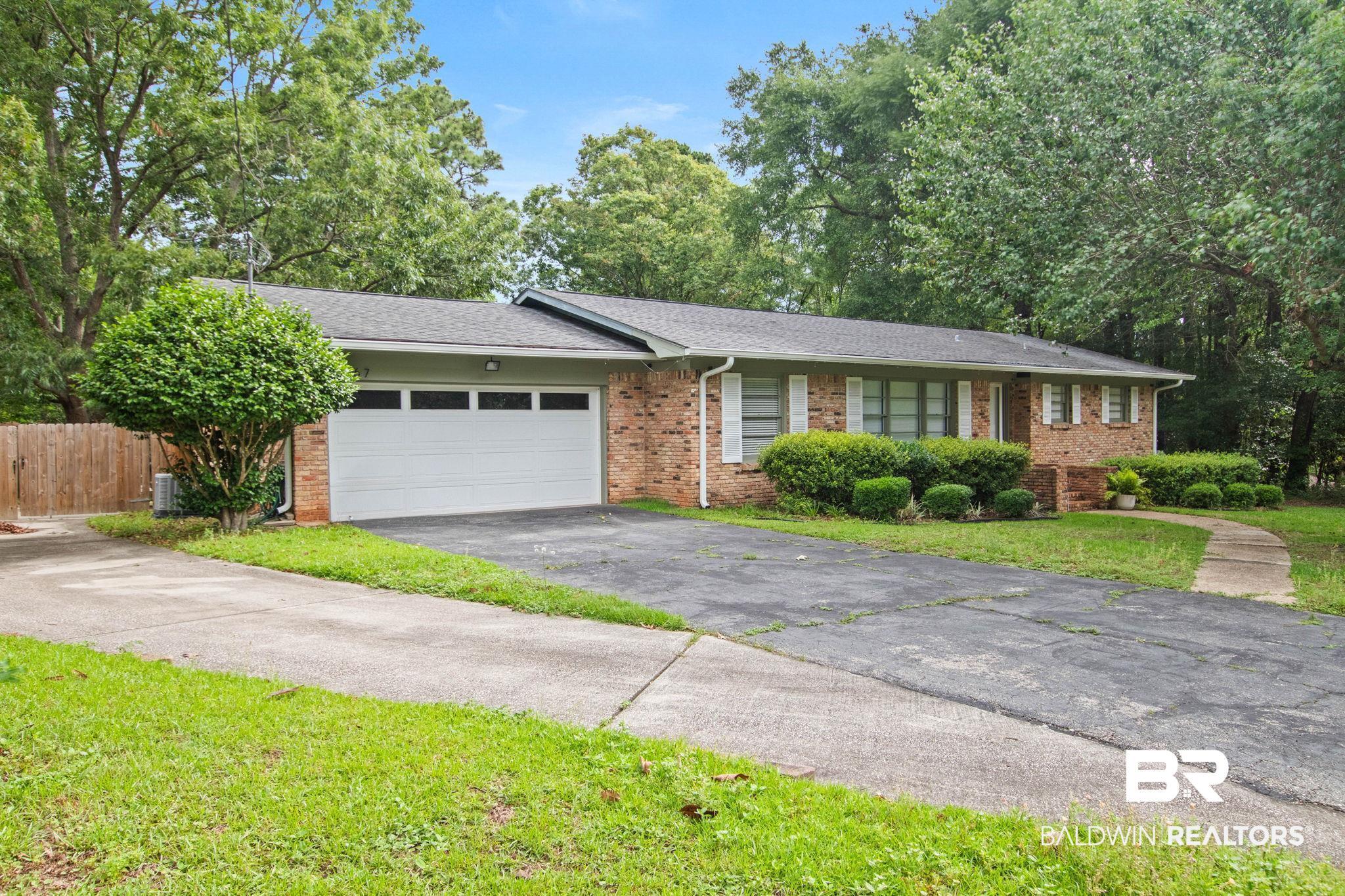 Image 3: Brick exterior residence featuring a two-car garage with transom windows, a concrete walkway, and established foundation plantings