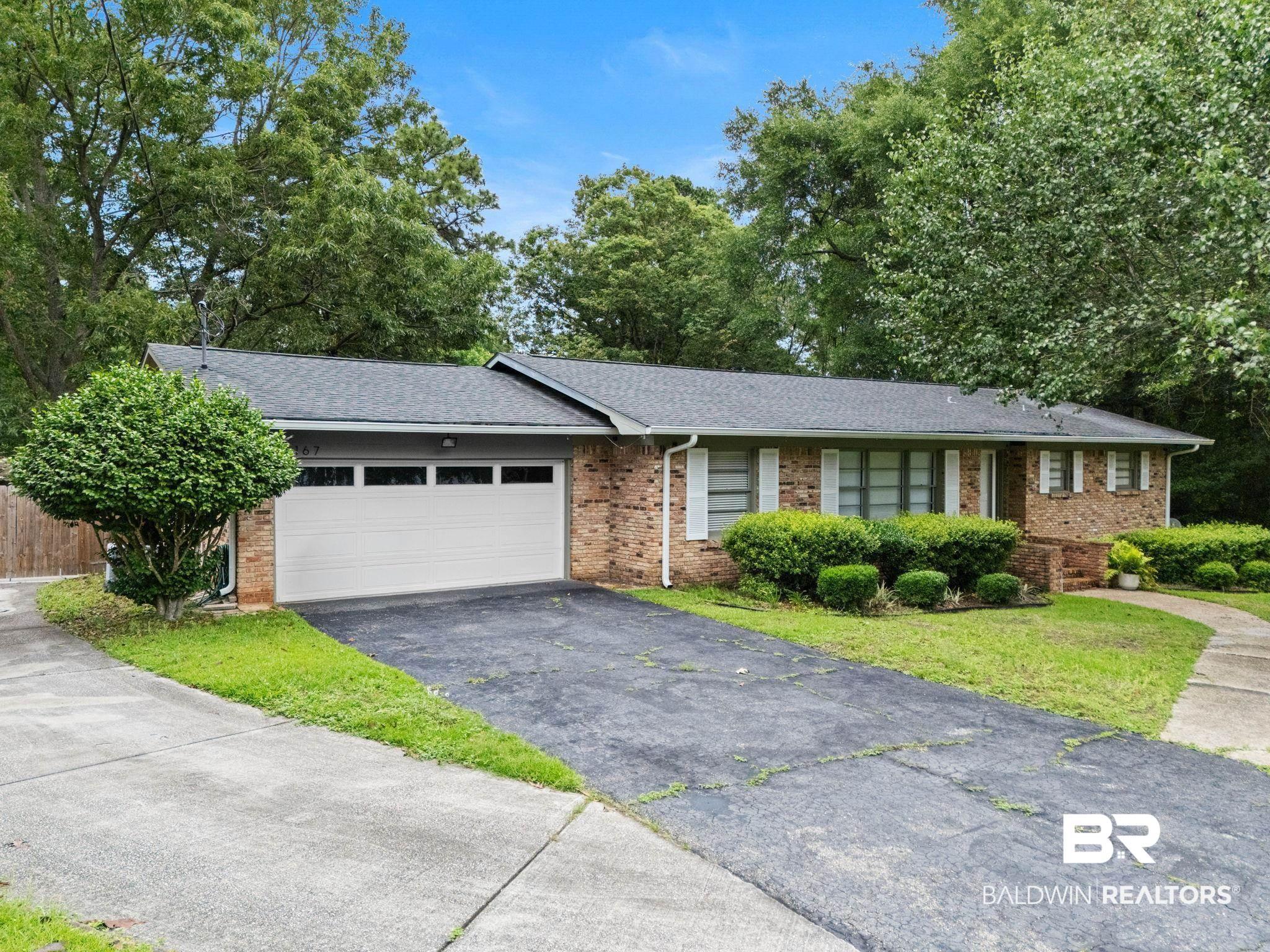 Image 4: Brick ranch-style residence featuring a dark shingle roof, white garage door, and white window shutters