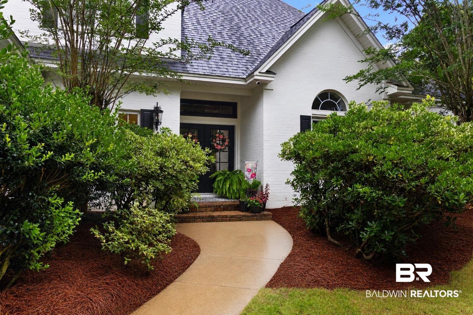 Image 2: White brick exterior with a dark shingle roof and a curved concrete pathway