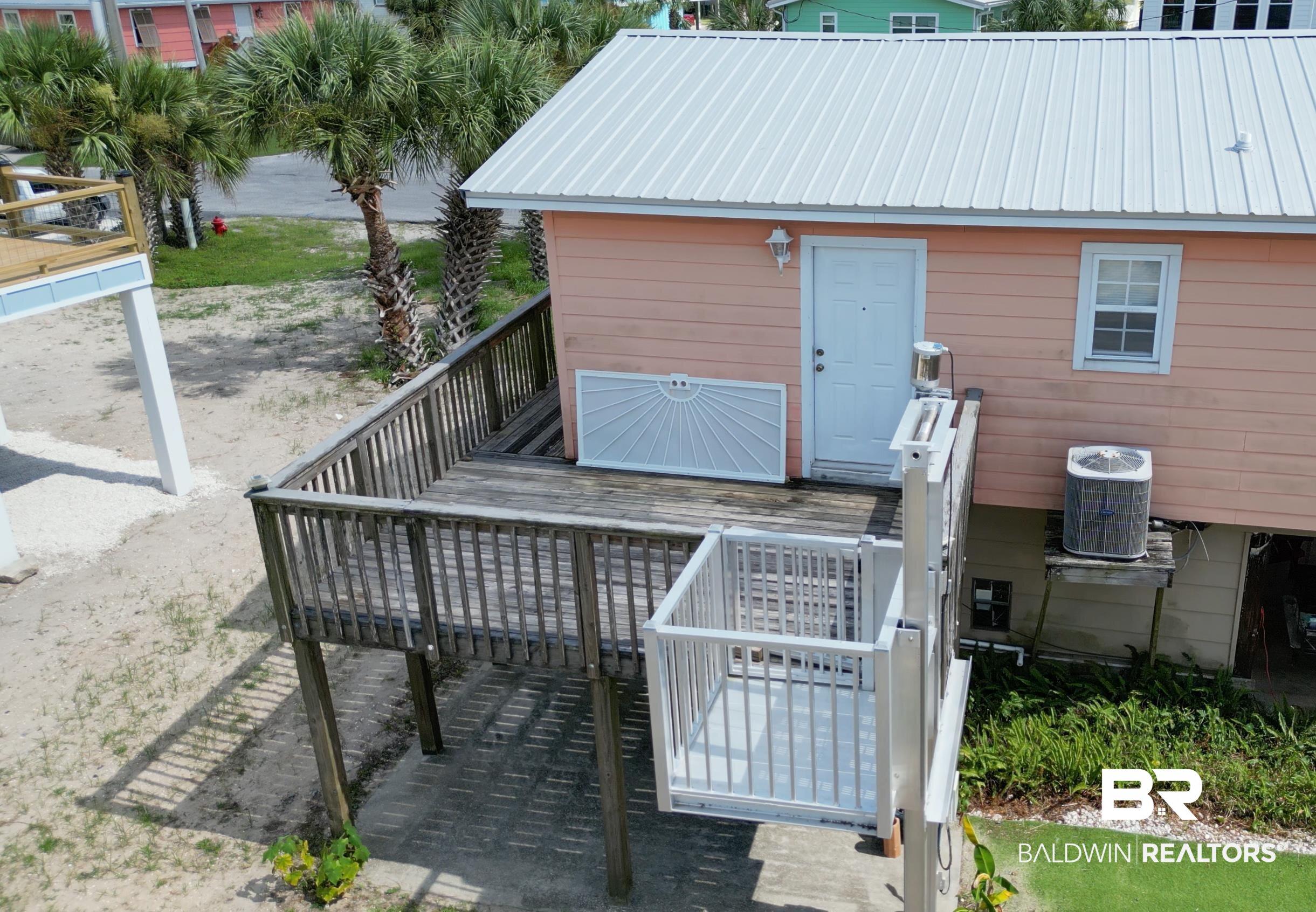 Image 4: Raised deck with a vertical lift system, featuring a standing seam metal roof and a light-colored exterior facade
