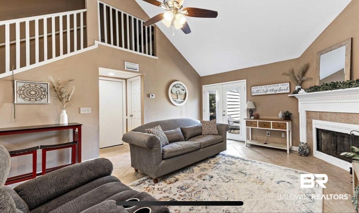 Image 3: Living area with a ceiling fan, a fireplace, lofted ceiling, tile patterned floors, and french doors