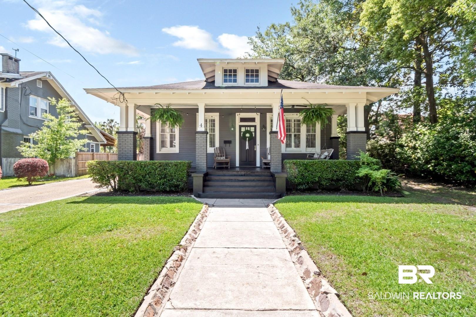 Image 1: Craftsman-style residence featuring a prominent front porch with white columns, dark gray siding, a central dormer, and a well-maintained lawn with mature landscaping