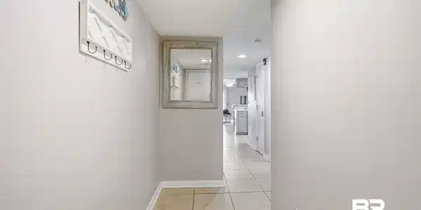 Image 2: Hallway featuring light neutral wall paint, tile flooring, and white trim