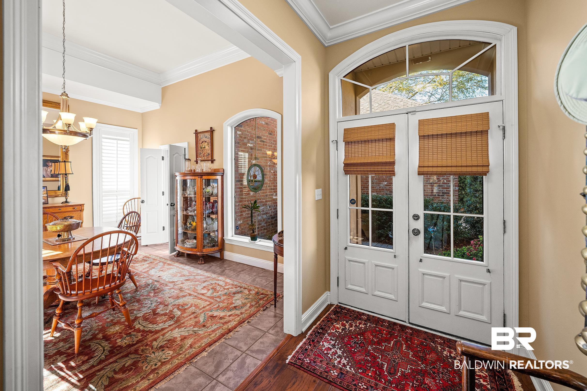 Image 4: Foyer featuring french doors, crown molding, dark tile patterned flooring, and a chandelier