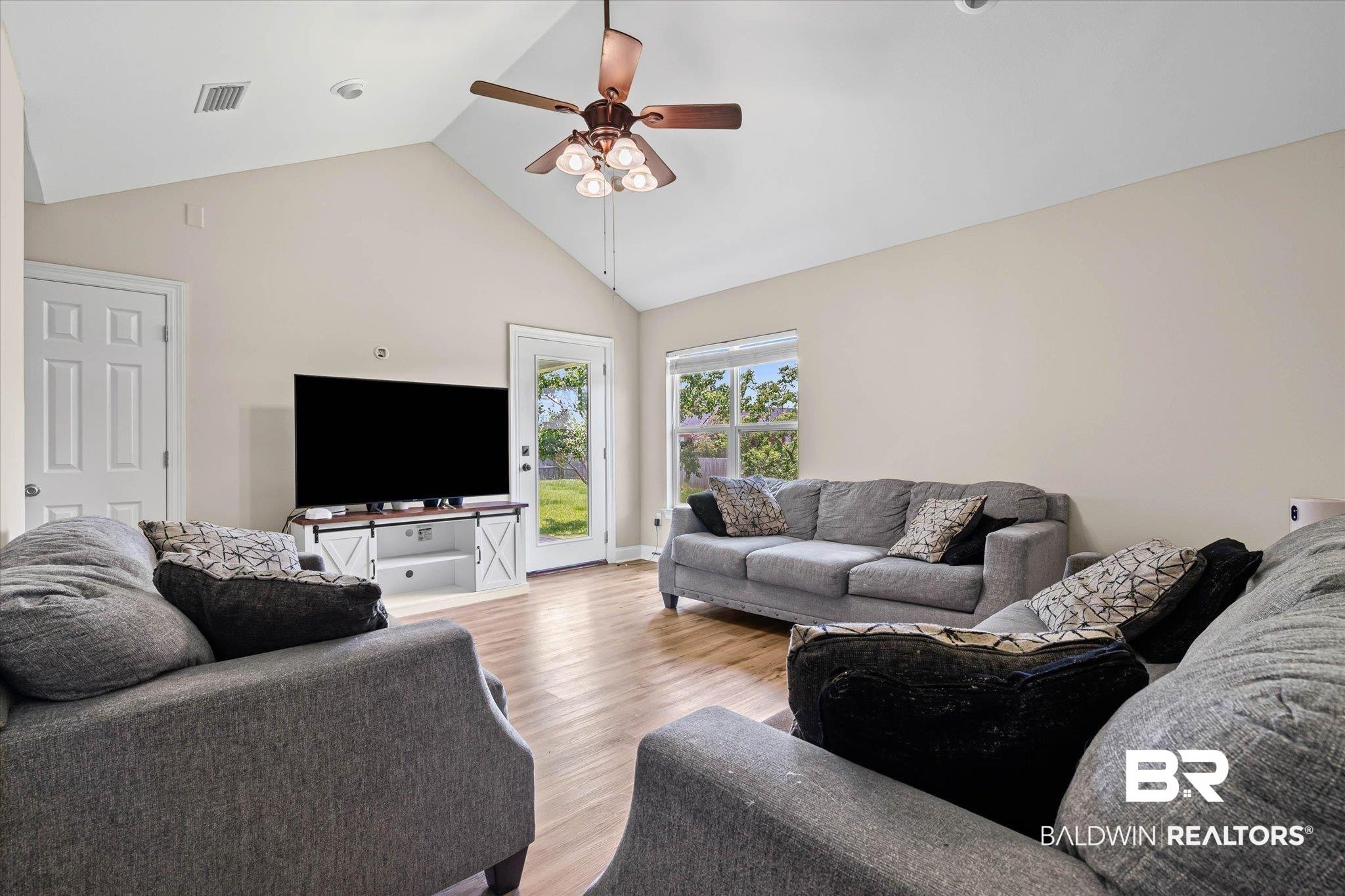 Image 2: Spacious living area featuring a vaulted ceiling and wood-finish flooring
