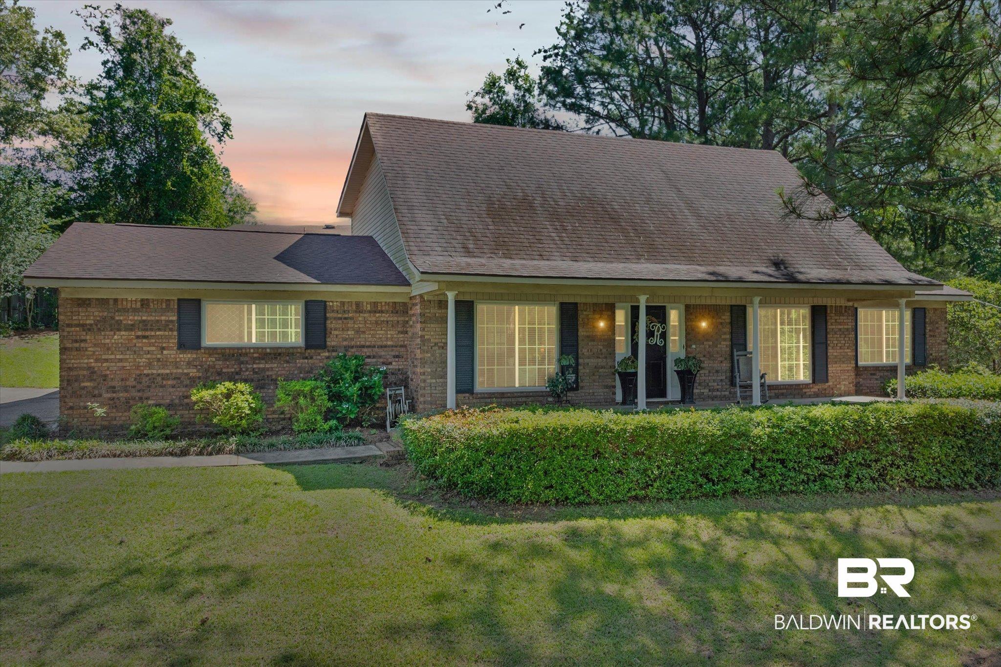 Image 1: Brick exterior featuring dark shutters and a covered front porch