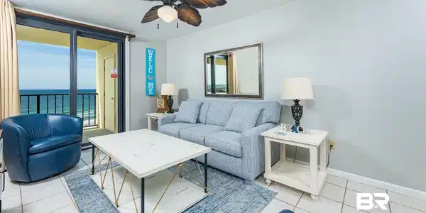 Image 2: Living area featuring a sliding glass door to a balcony, ceramic tile flooring, a ceiling fan with leaf-shaped blades, light gray walls, and a decorative wall mirror