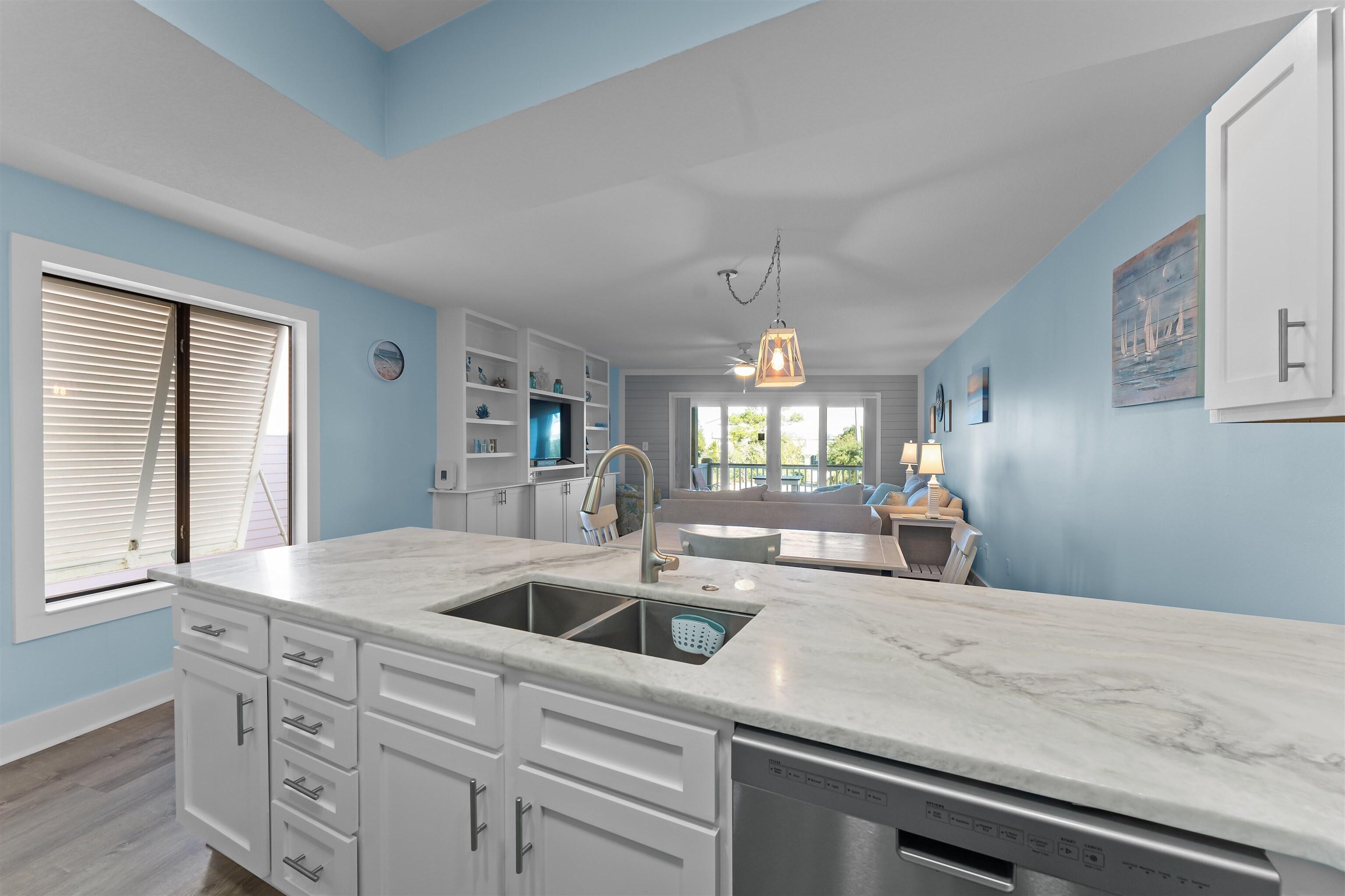 Image 3: Kitchen featuring white cabinets, light stone counters, stainless steel dishwasher, open floor plan, and light wood-type flooring