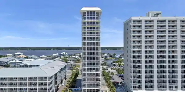 Image 2: Modern high-rise tower with multiple balconies, a ground-level pool, and direct beach access via a wooden boardwalk