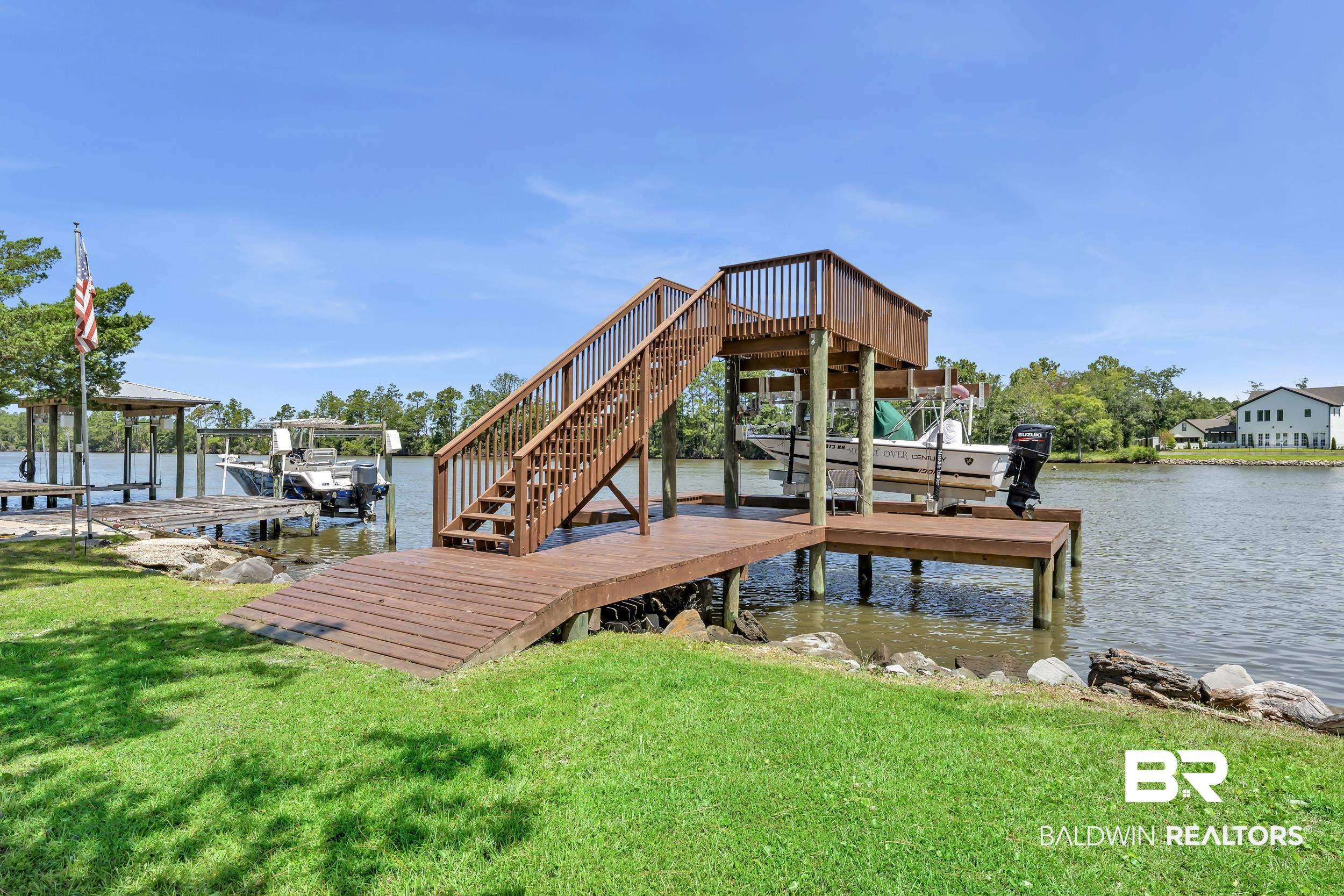 Image 2: Waterfront property featuring a multi-level boat dock with a covered slip and boat lift