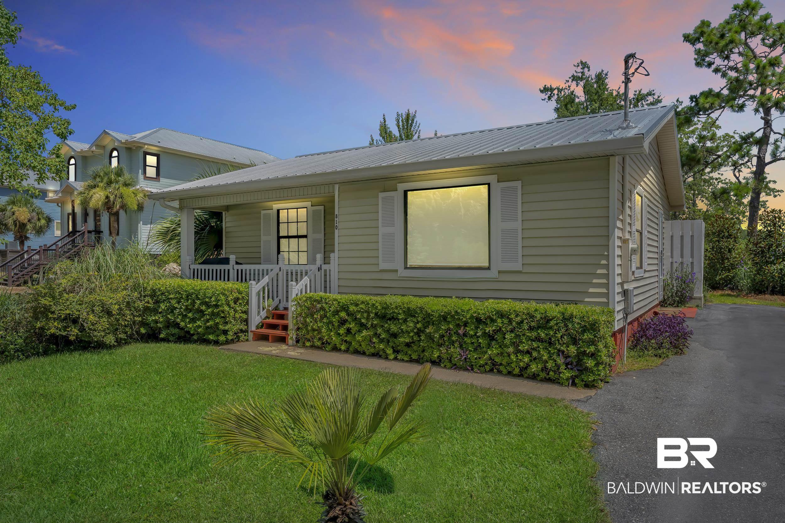 Image 3: Light green siding exterior featuring a covered porch with white railings, a metal roof, and white shutter accents