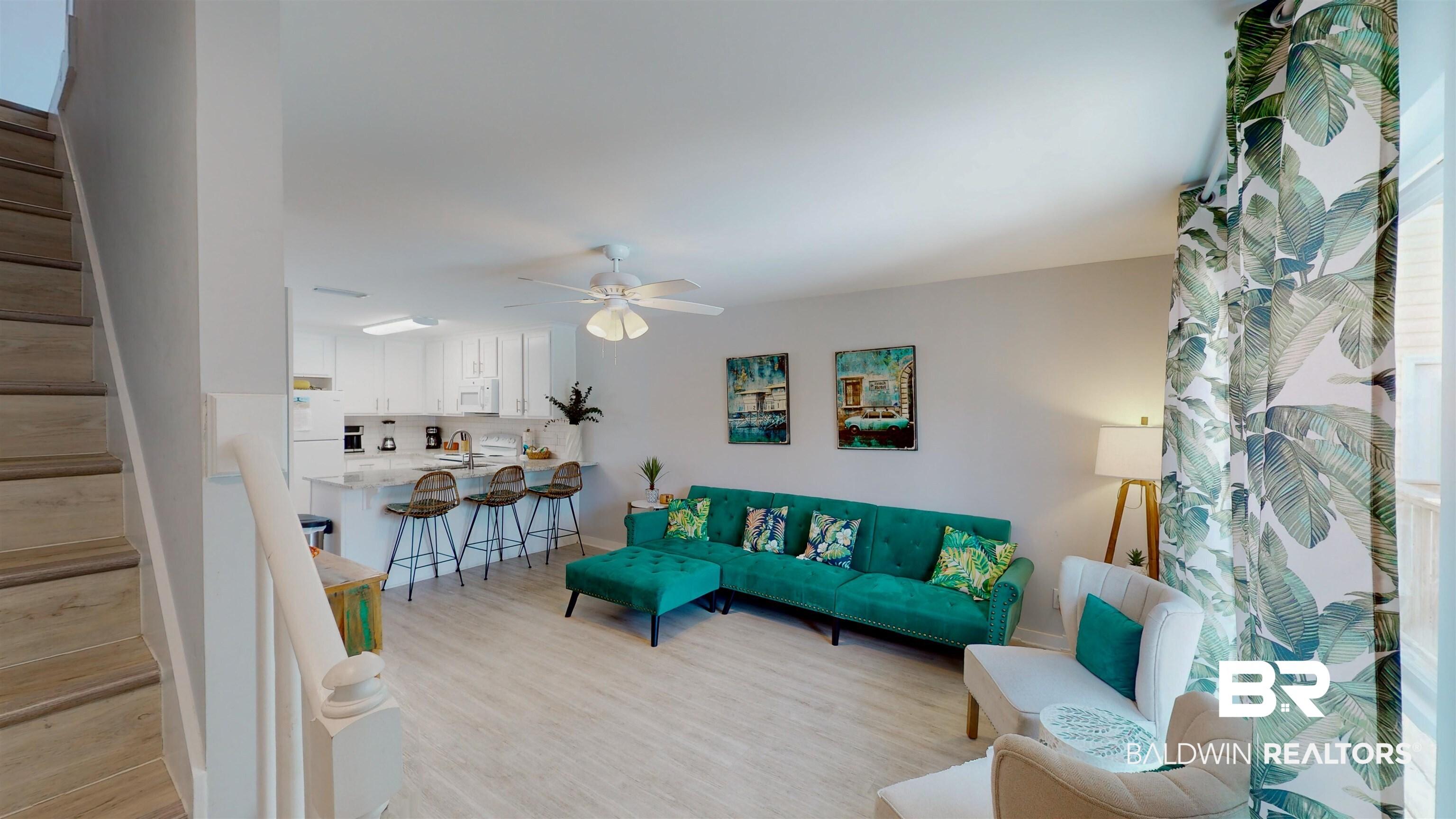 Image 2: Living area featuring stairway, light wood-style flooring, and ceiling fan