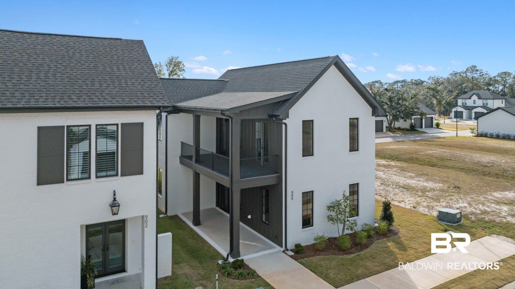 Image 2: Rear view of property with a yard, a shingled roof, stucco siding, and a balcony