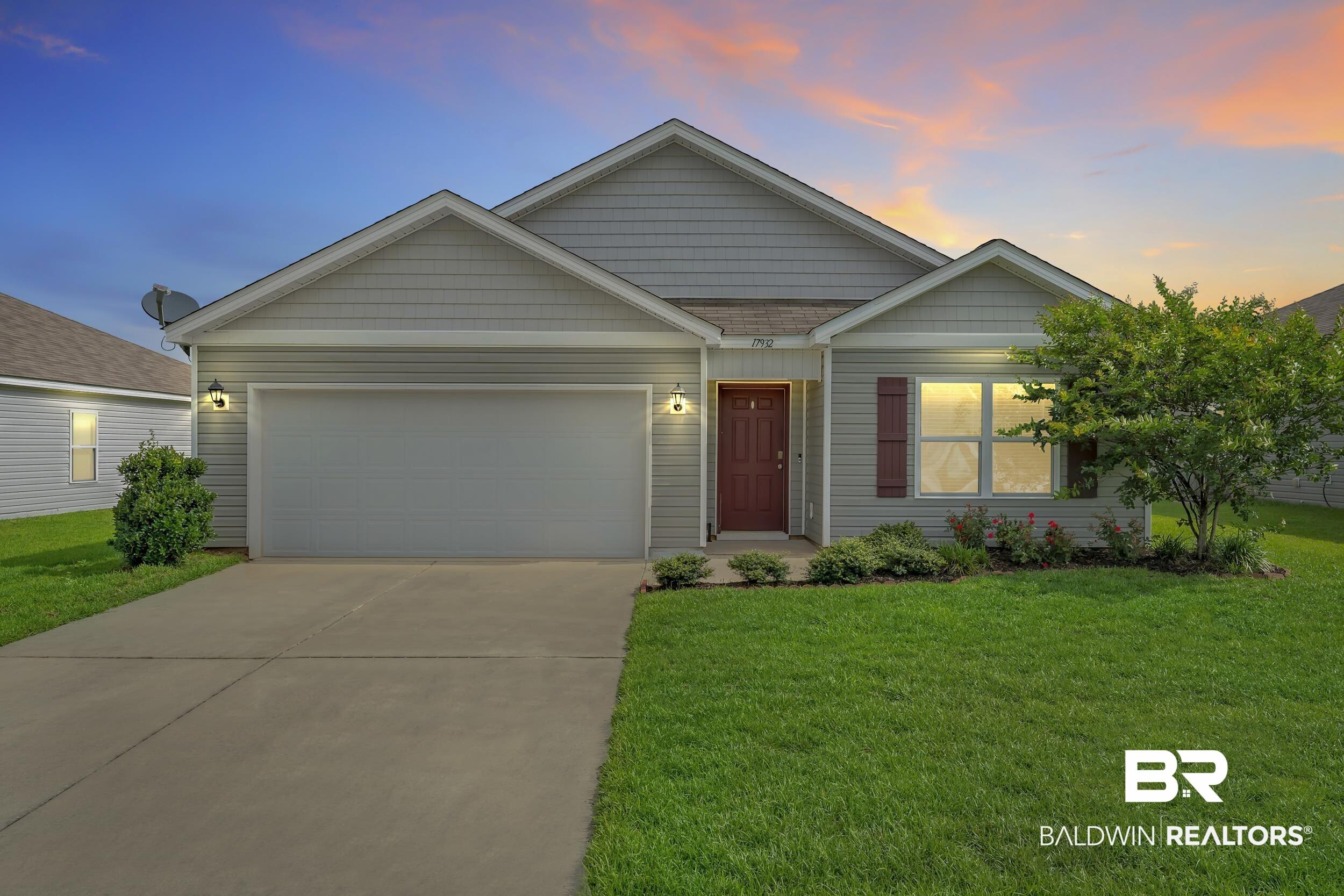 Image 2: Single-story residence featuring light gray siding, a prominent attached garage, and a concrete driveway