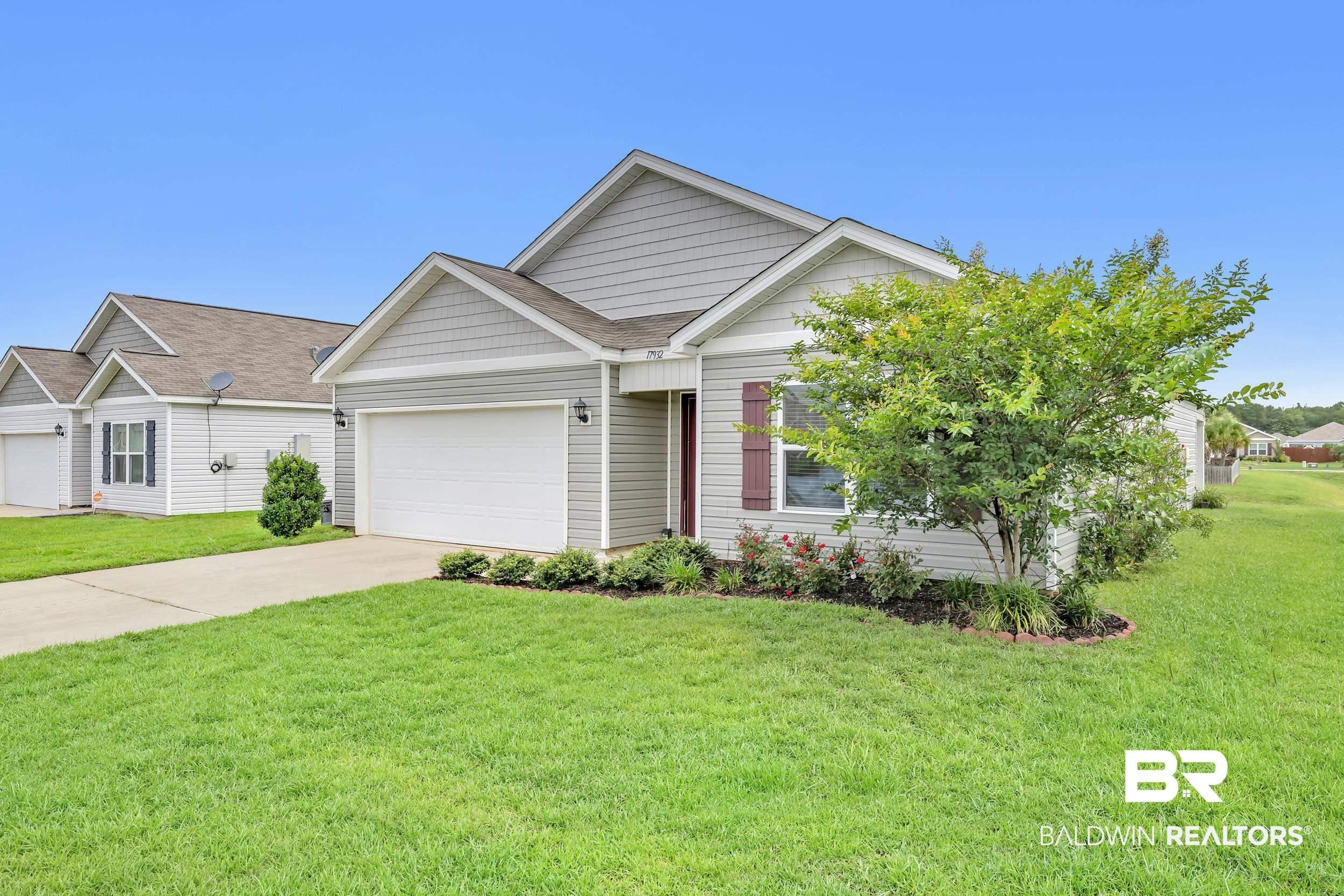 Image 4: Single-story residence featuring gray siding with white trim, a brown shingle roof, and a two-car garage