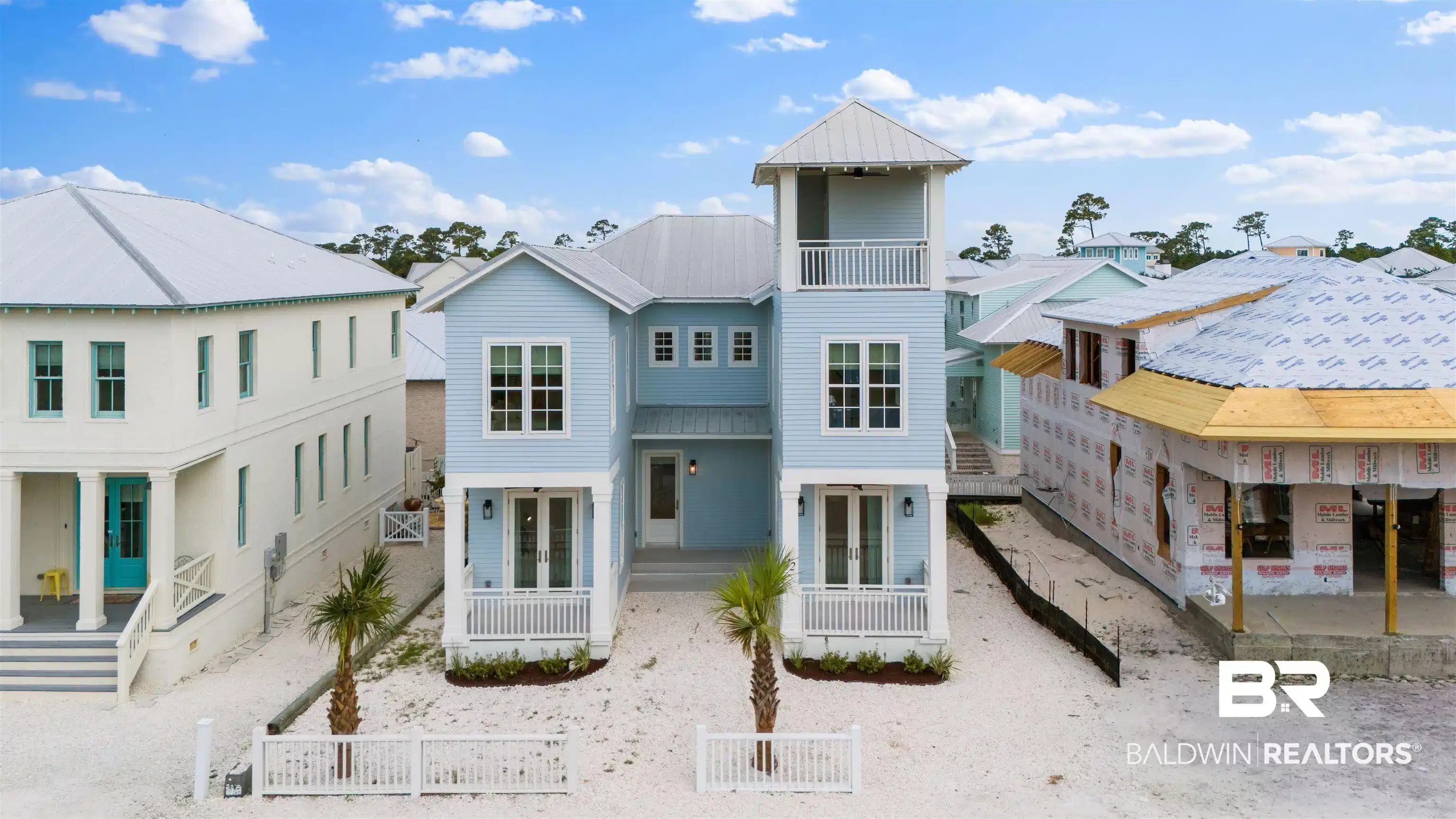 Image 1: Coastal-style residence featuring light blue siding, white trim, a metal roof, and a prominent observation tower with a balcony