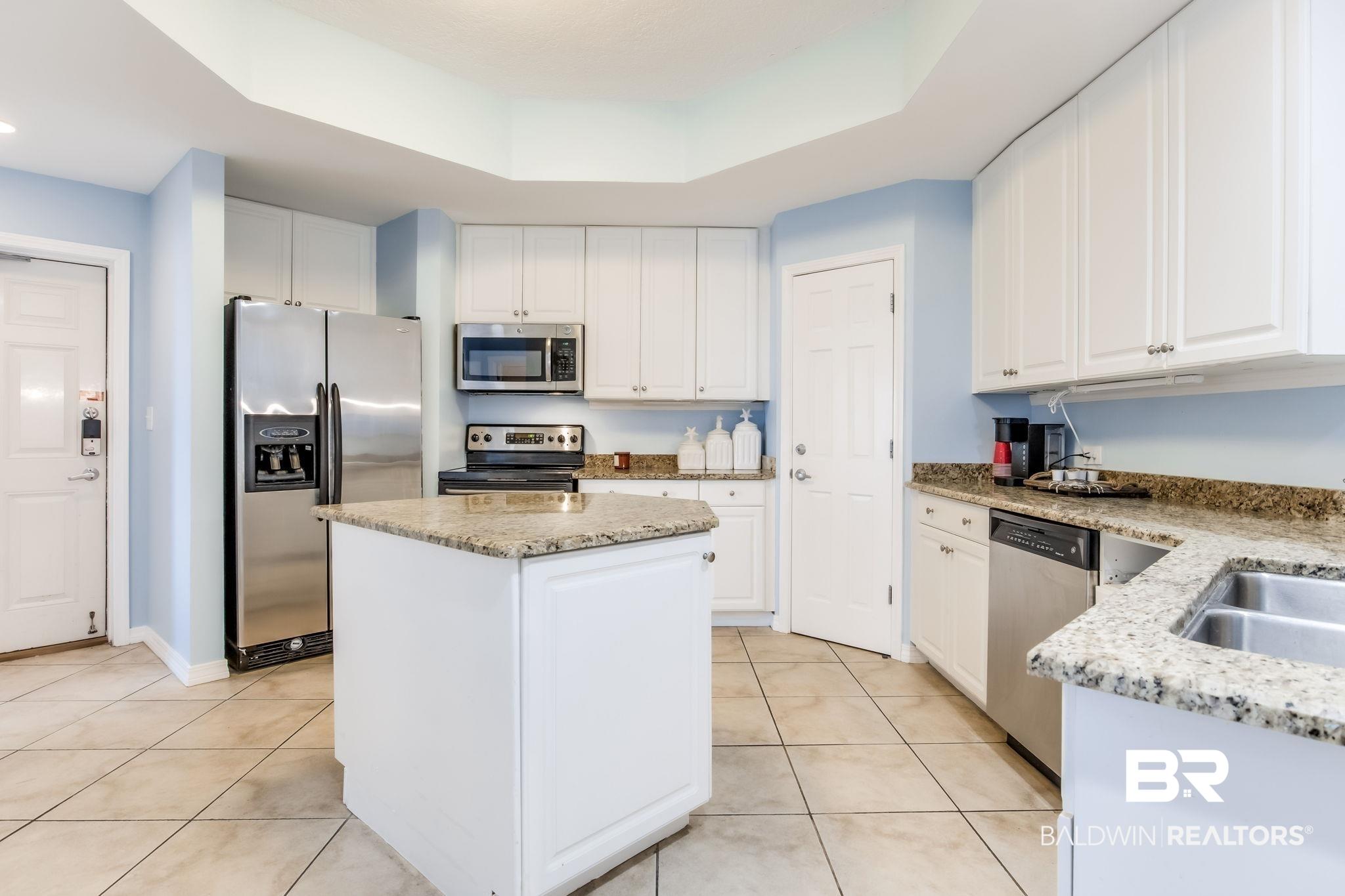 Image 4: Kitchen featuring appliances with stainless steel finishes, light tile patterned floors, a kitchen island, white cabinets, and recessed lighting
