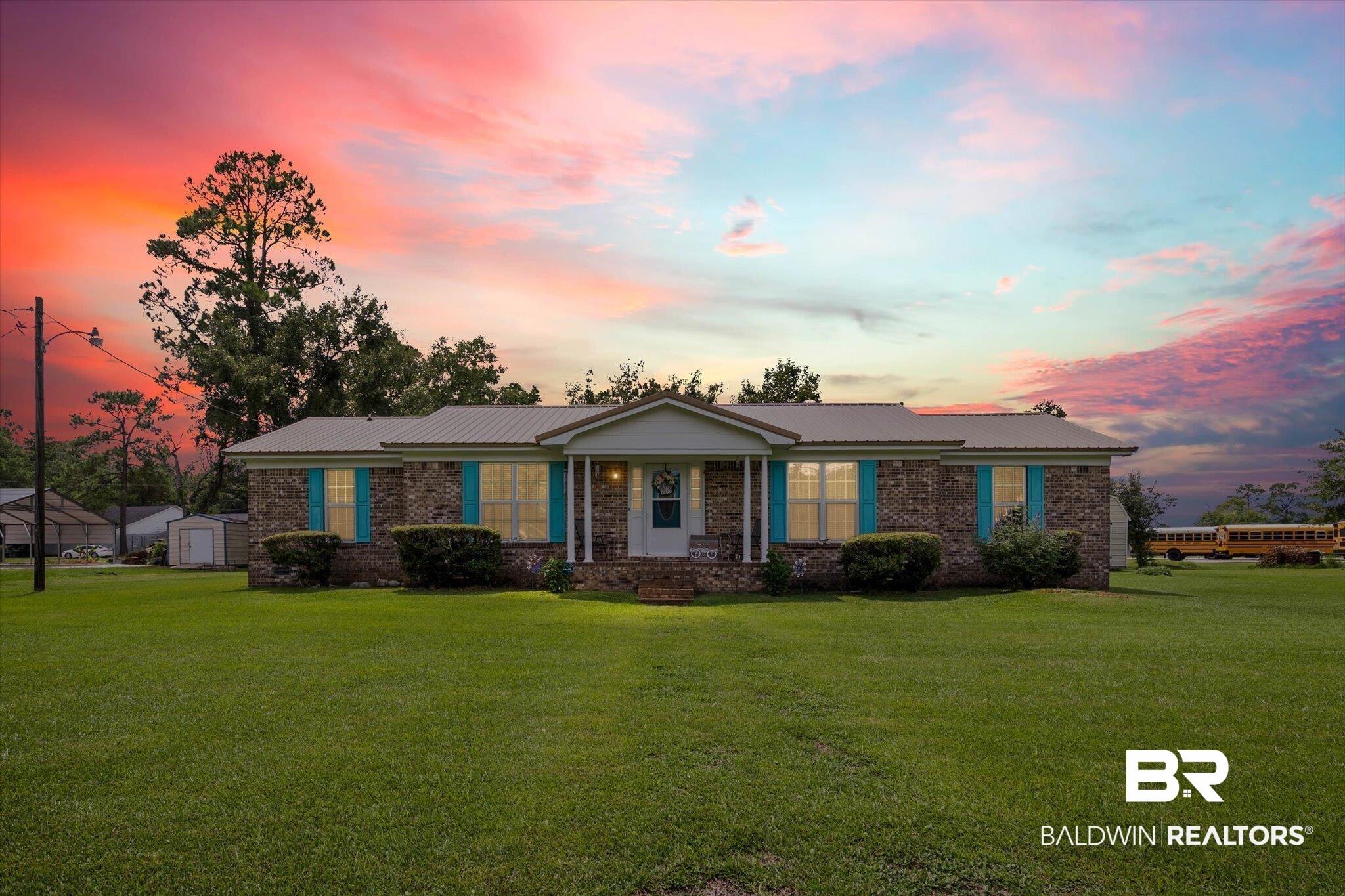 Image 1: View of front of property featuring a lawn, a metal roof, brick siding, and covered porch