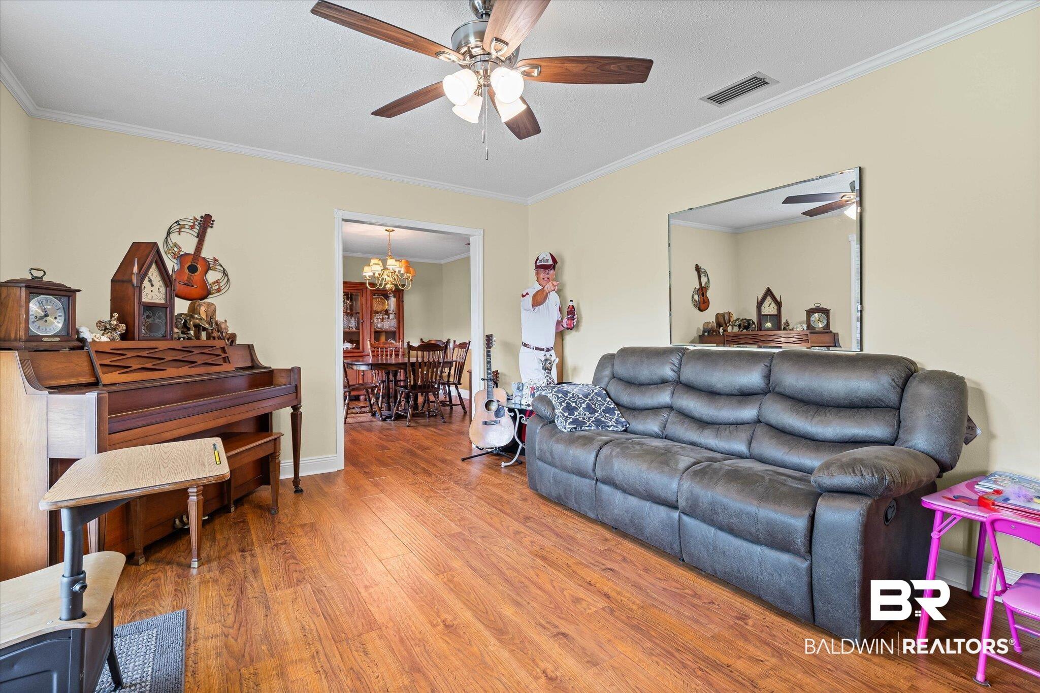 Image 2: Living room featuring crown molding, wood finished floors, a chandelier, and ceiling fan