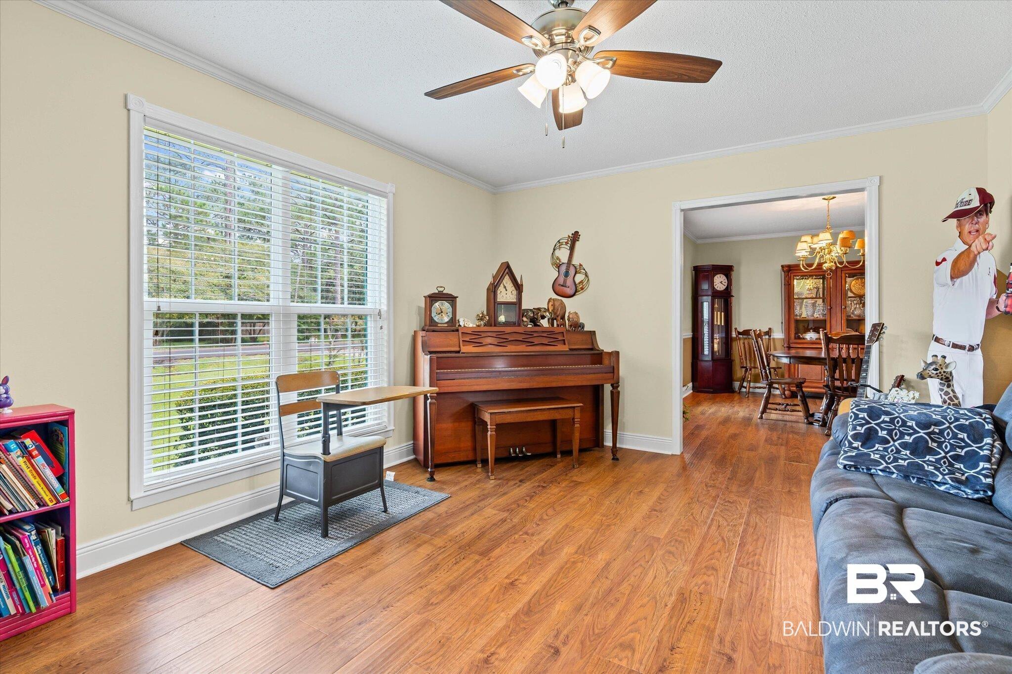 Image 3: Living area featuring plenty of natural light, light wood-style floors, crown molding, and ceiling fan