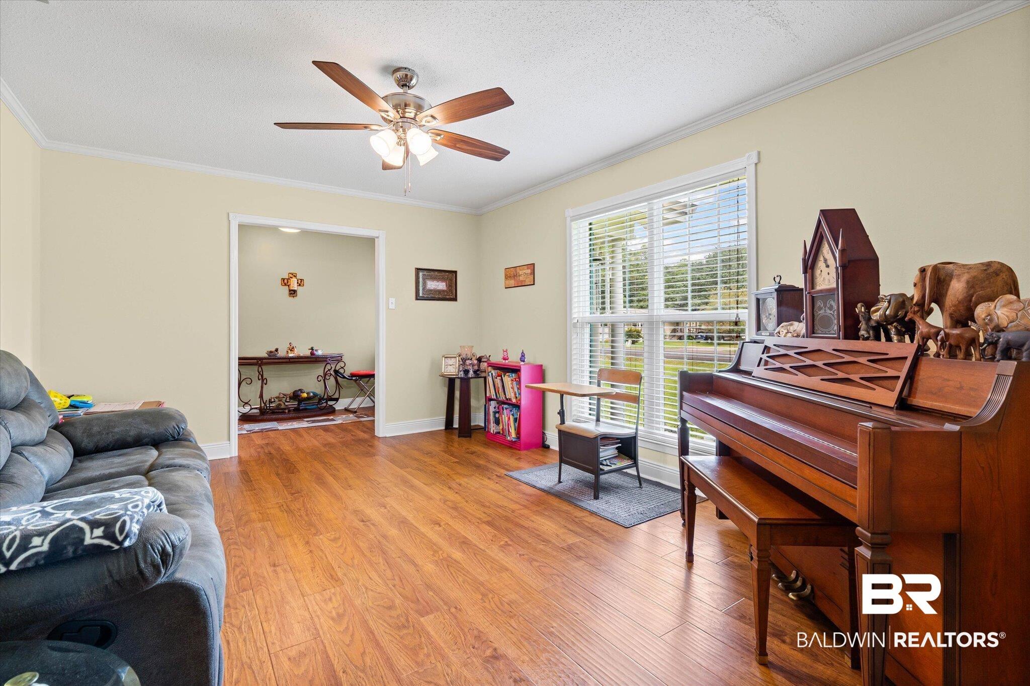 Image 4: Living room featuring ornamental molding, light wood-style flooring, a textured ceiling, and a ceiling fan