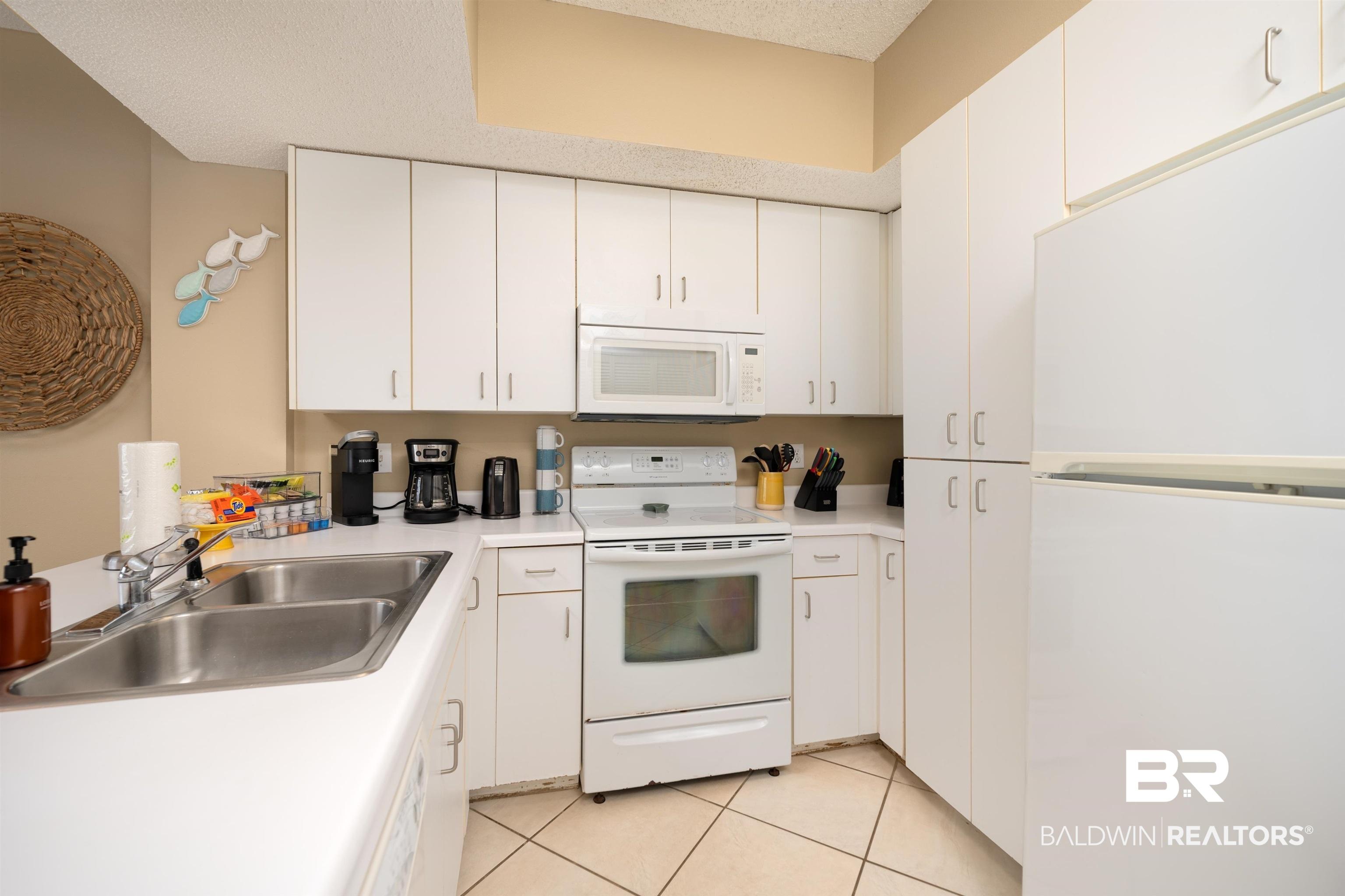 Image 2: Kitchen featuring white appliances, white cabinetry, light countertops, and a textured ceiling