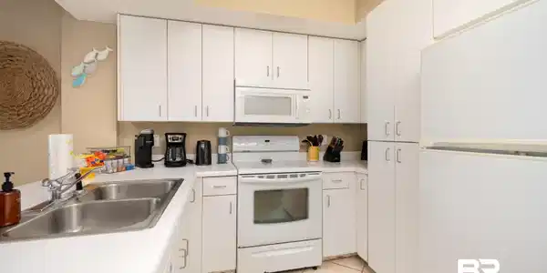 Image 2: Kitchen featuring white appliances, white cabinetry, light countertops, and a textured ceiling