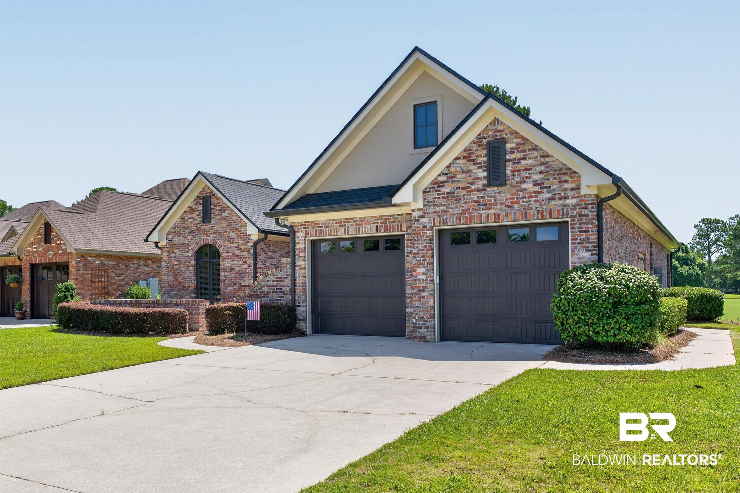 Image 2: Brick and stucco exterior with a multi-level roofline, two dark panel garage doors with window inserts, and an upper gable window