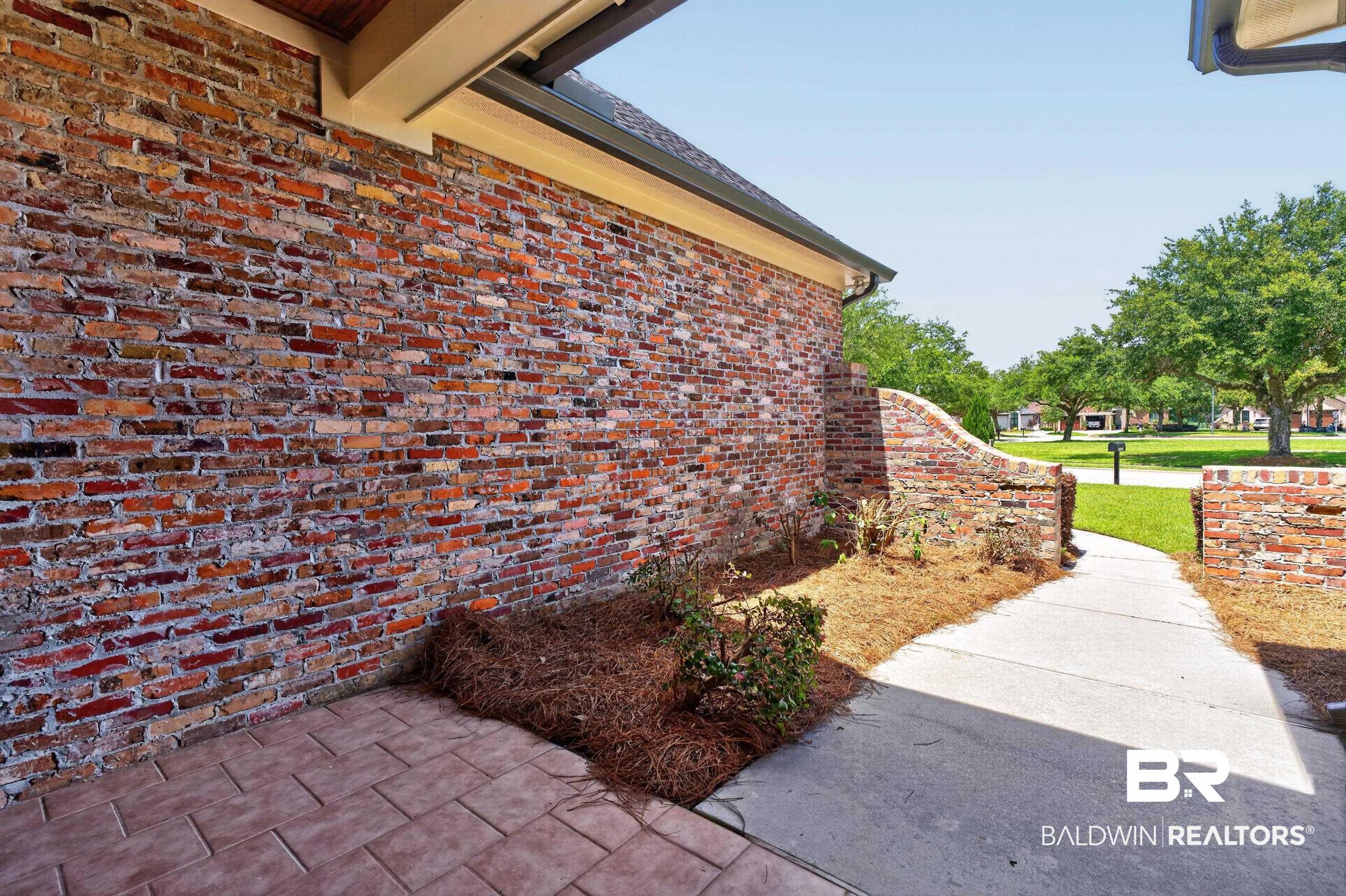 Image 4: Multi-hued brick exterior with a soffited overhang and a paved patio area