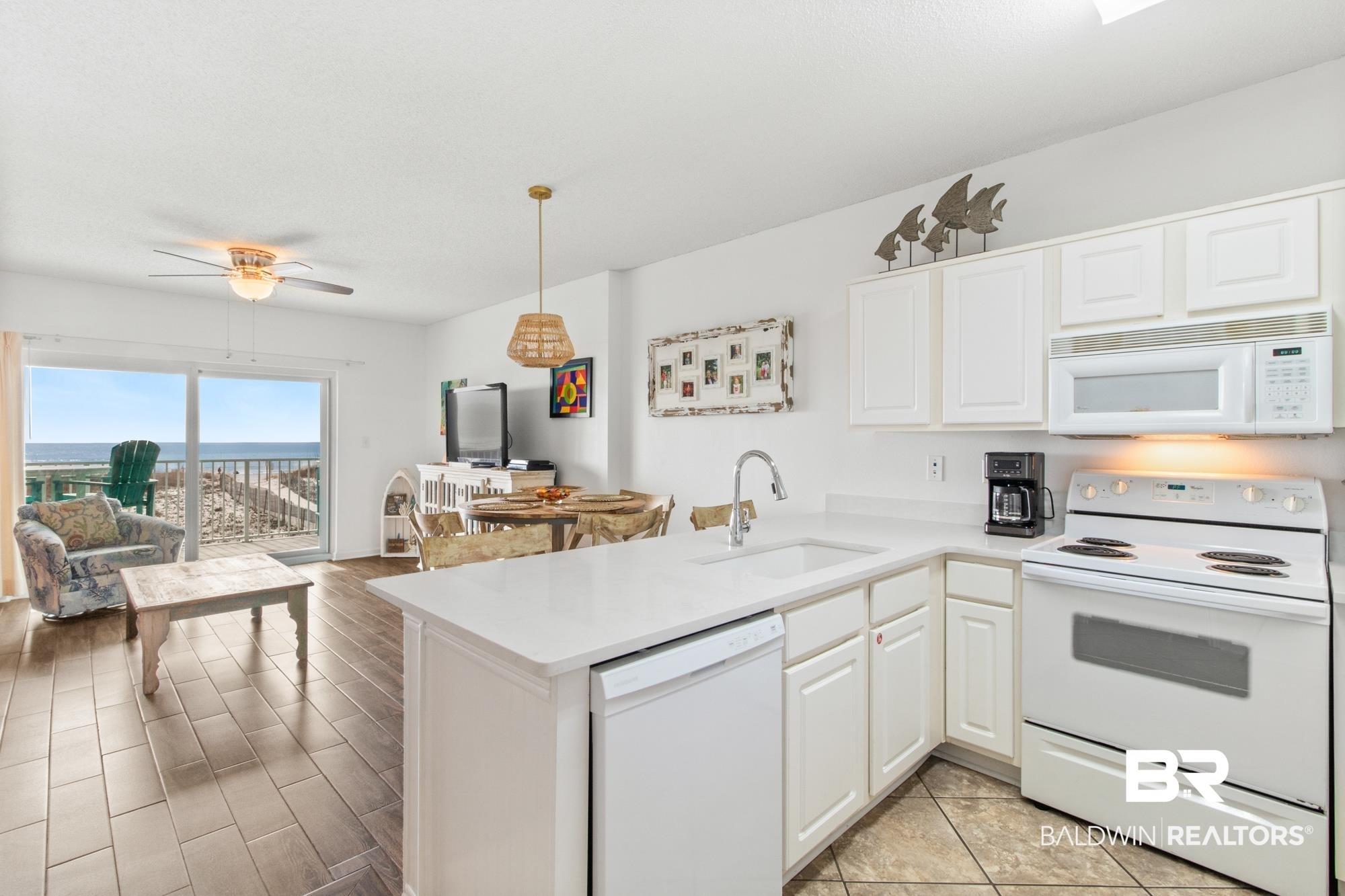 Image 2: Kitchen with sink, white cabinets, white appliances, and kitchen peninsula