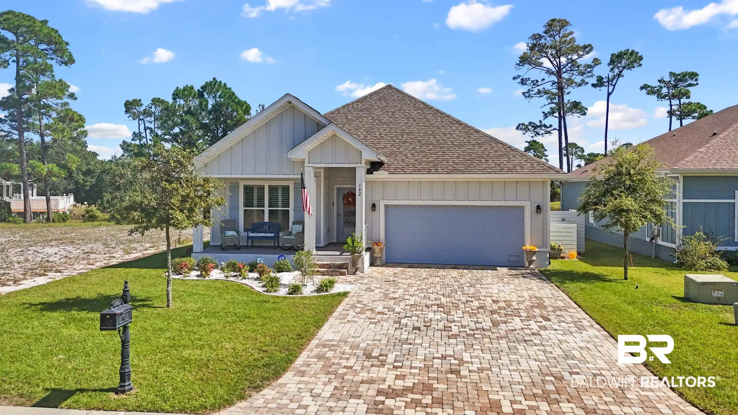 Image 1: View of front of property with board and batten siding, decorative driveway, a front yard, a shingled roof, and an attached garage