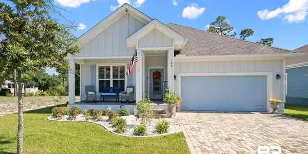 Image 2: View of front of property featuring a porch, board and batten siding, decorative driveway, roof with shingles, and a front lawn