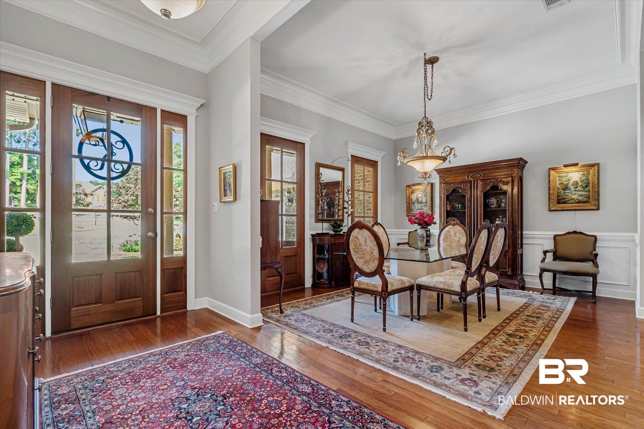 Image 3: Wood-finish flooring throughout, featuring a double glass-paned entry door with sidelights, crown molding, and wainscoting