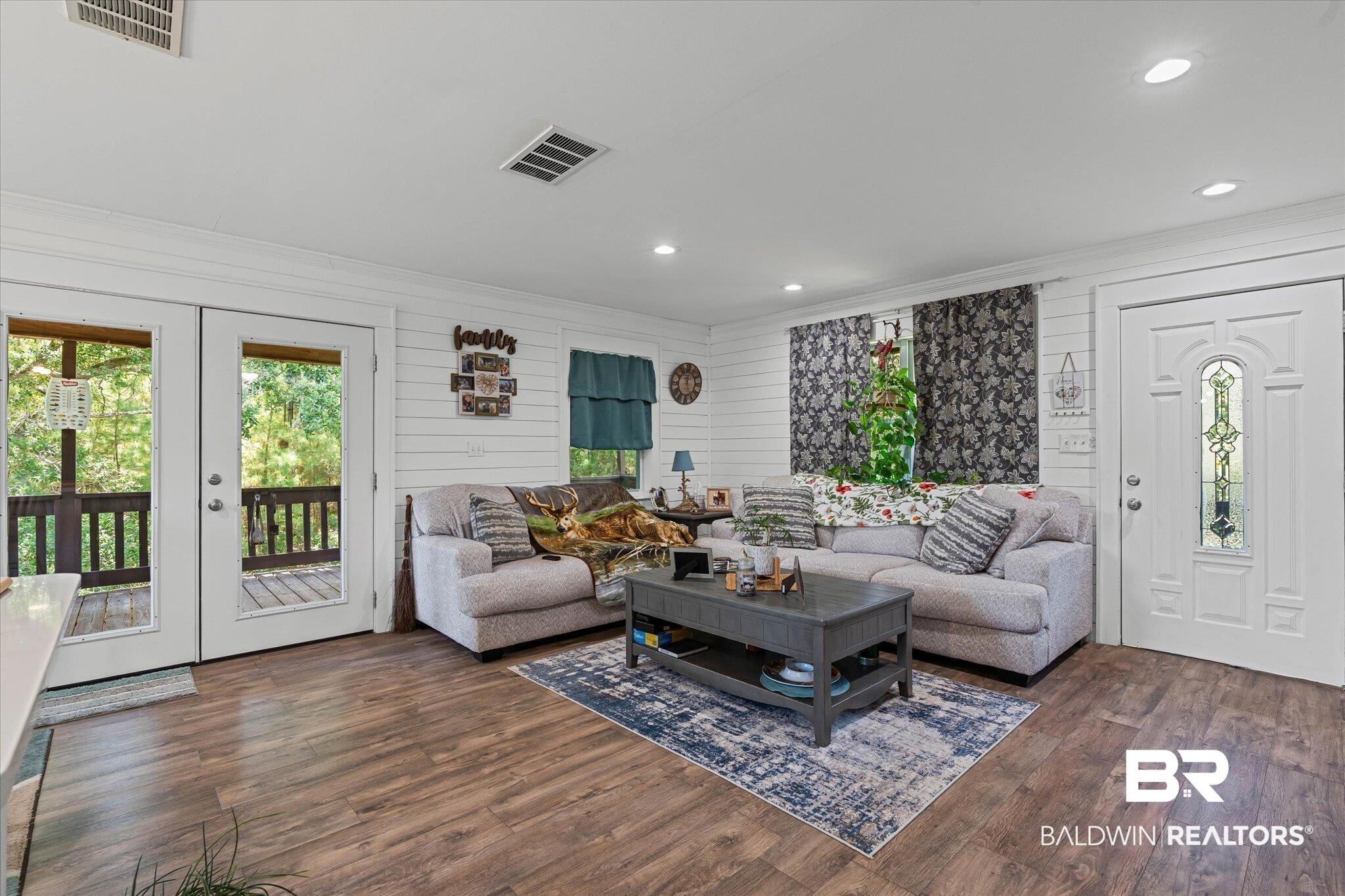 Image 4: Living room with plenty of natural light, dark wood-style floors, recessed lighting, crown molding, and french doors