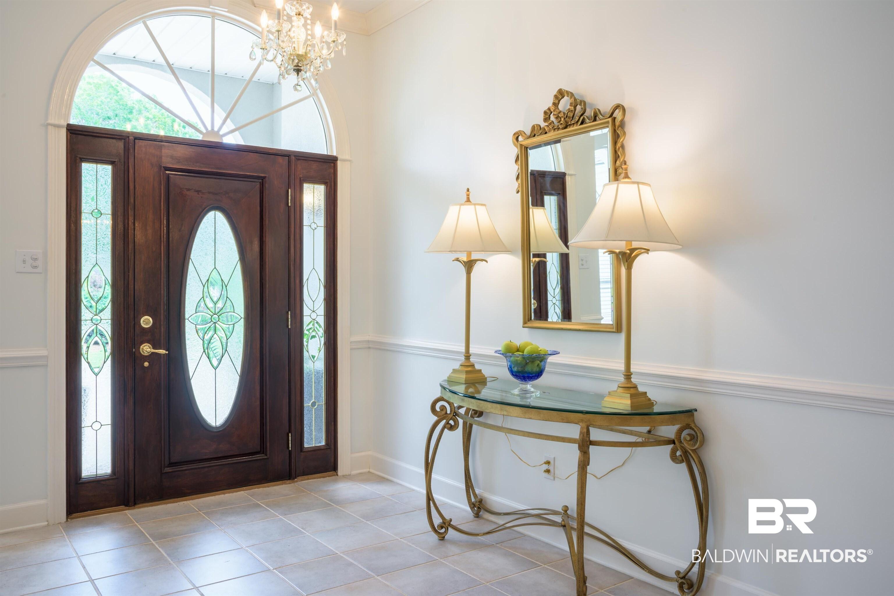 Image 3: Entrance foyer featuring suspended lighting, crown molding, and tile patterned flooring