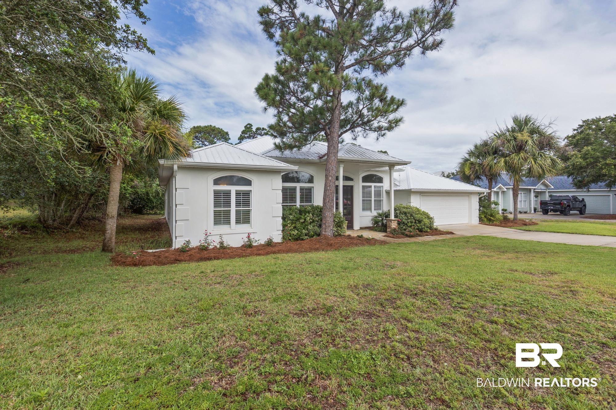 Image 4: White stucco exterior with a metal roof and an integrated two-car garage