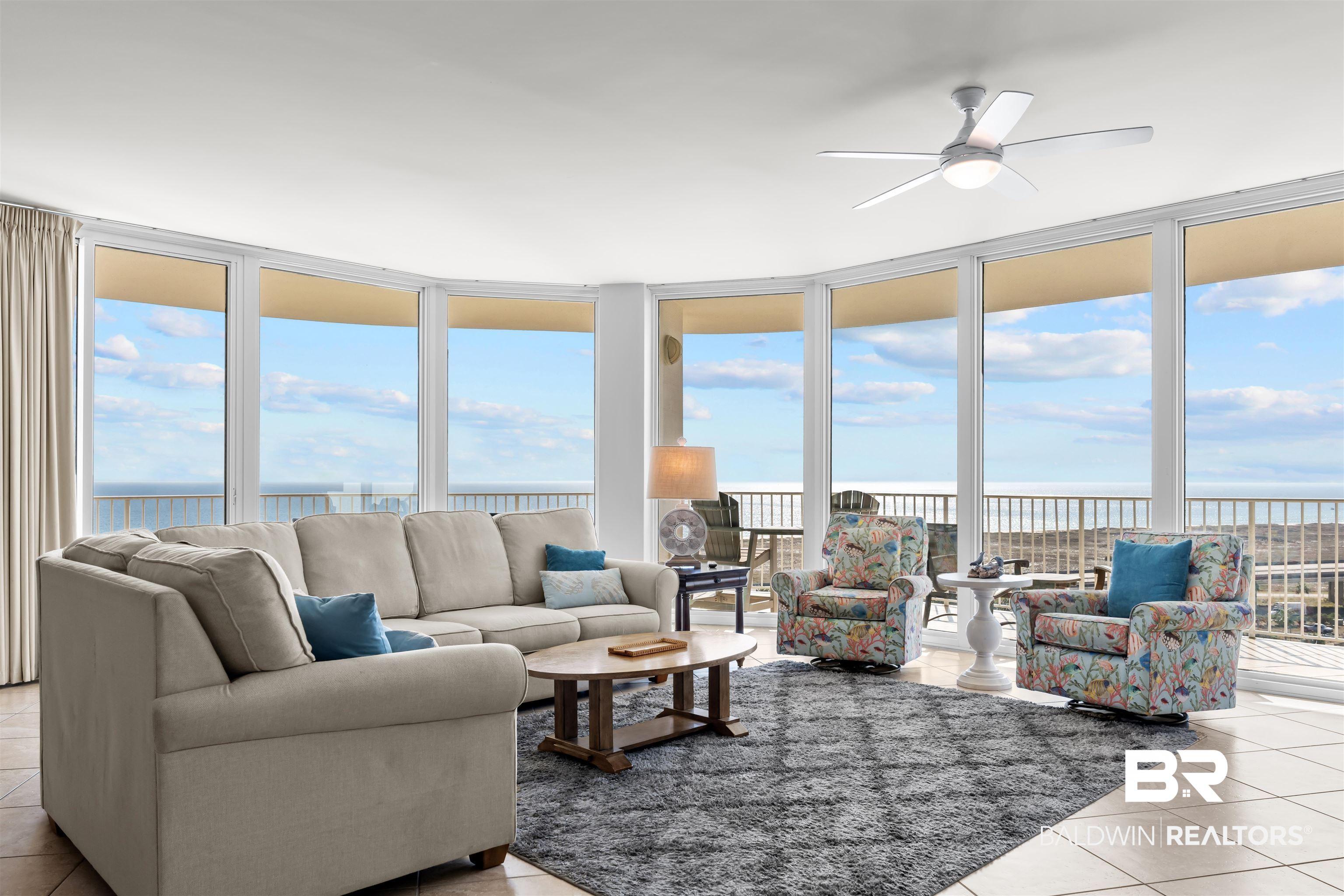 Image 2: Living room with light tile patterned flooring, expansive windows, a water view, and ceiling fan