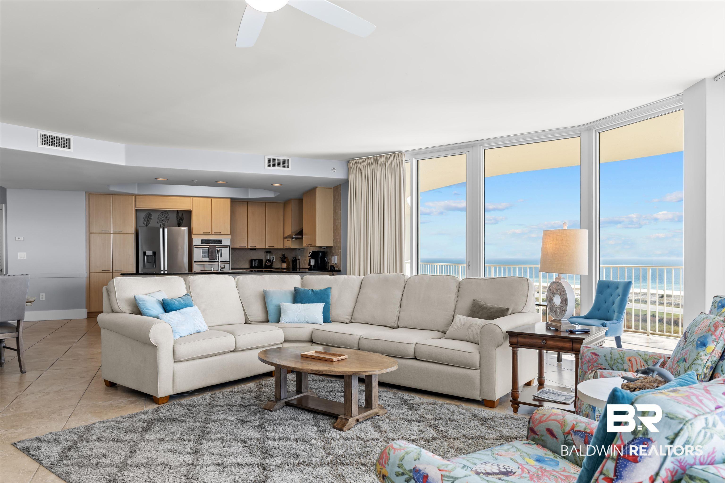 Image 3: Living area with a wall of windows, a water view, light tile patterned floors, and ceiling fan