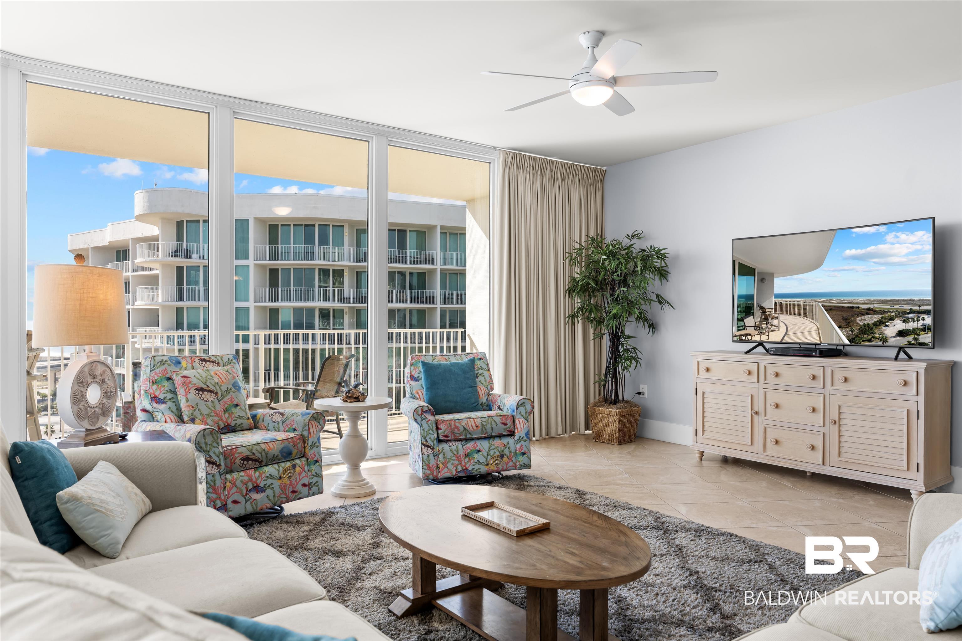 Image 4: Living area with healthy amount of natural light, light tile patterned floors, floor to ceiling windows, and a ceiling fan