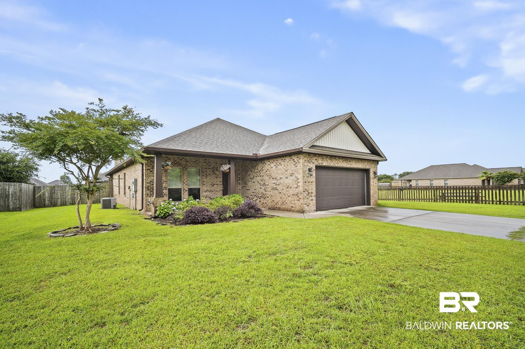Image 3: Brick exterior home featuring a two-car garage, established landscaping, and a manicured lawn